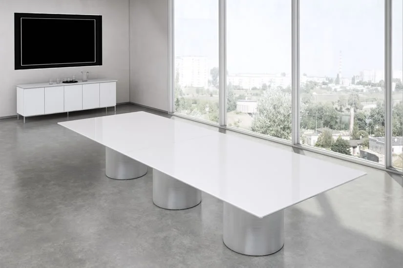 A large rectangle Drum conference room table with a white painted back glass tabletop and polished aluminum bases.