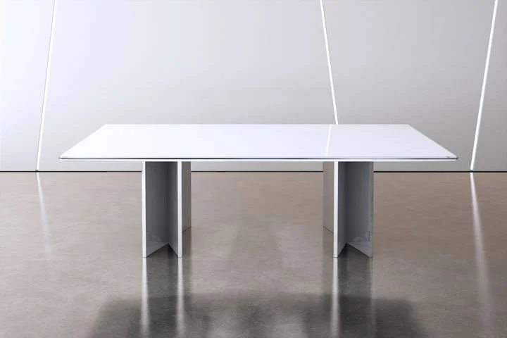 Modern white conference table with metallic legs in a minimalistic room with white walls and gray flooring.