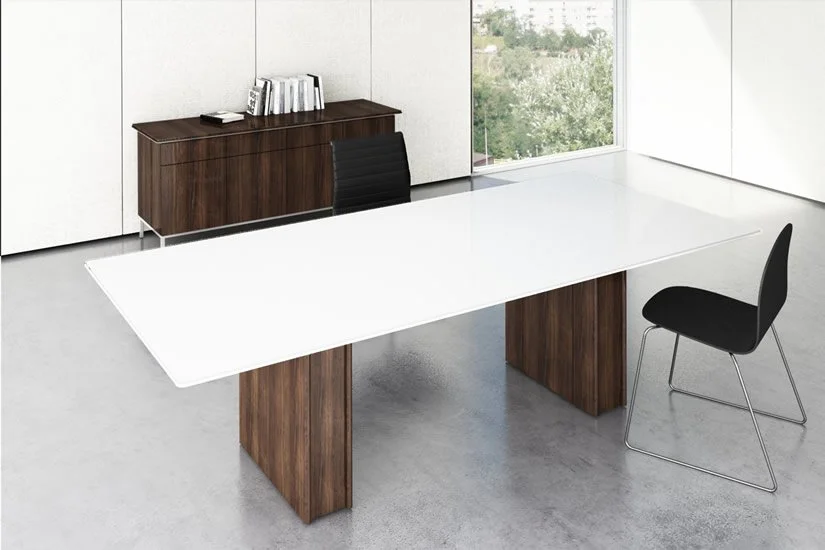 Panel conference room table with a white tabletop and wood veneer base. Large window showing trees outside.
