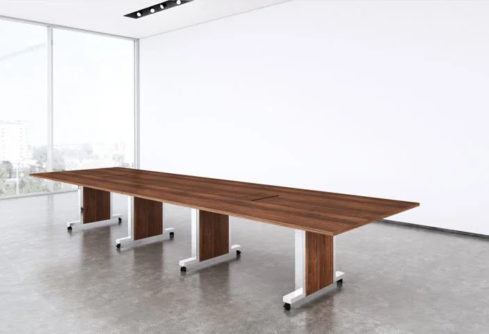 Modern conference room with a long wooden table and metal legs, bright natural light from large windows.