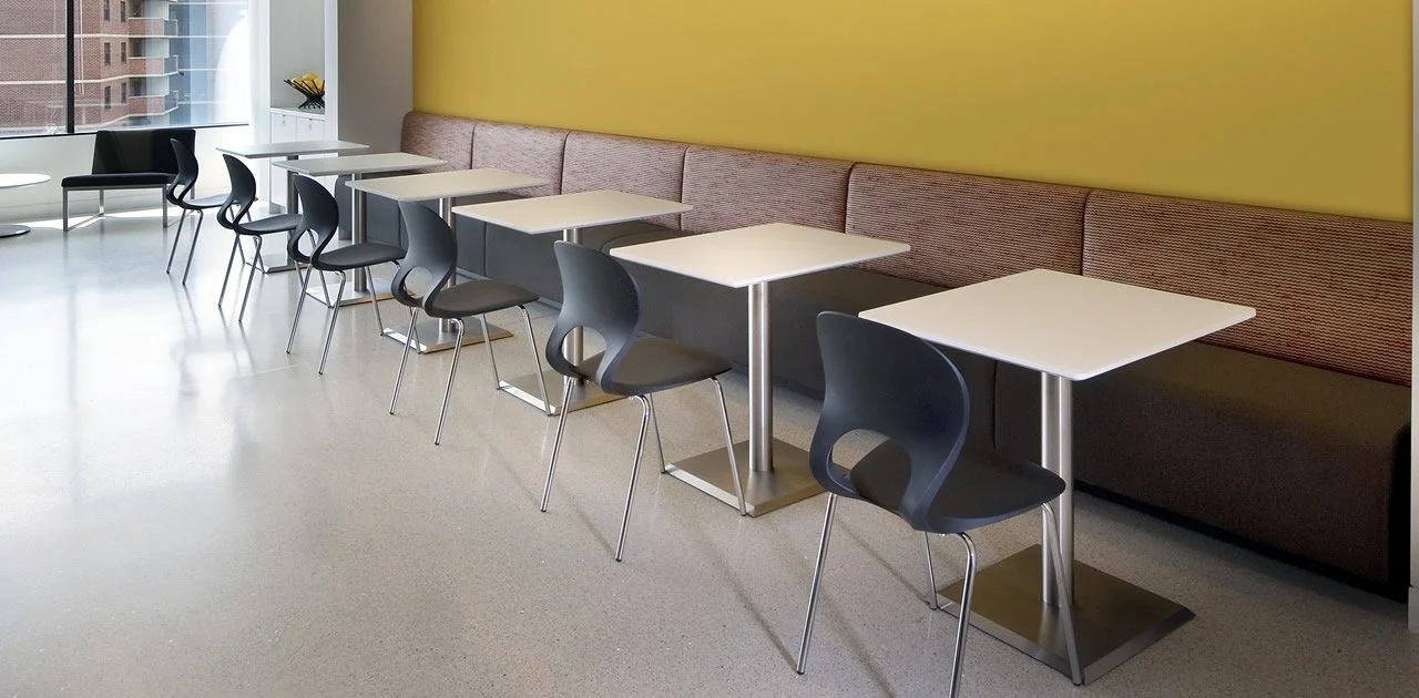 Cafe tables with white tabletops and brushed aluminum base finishes..