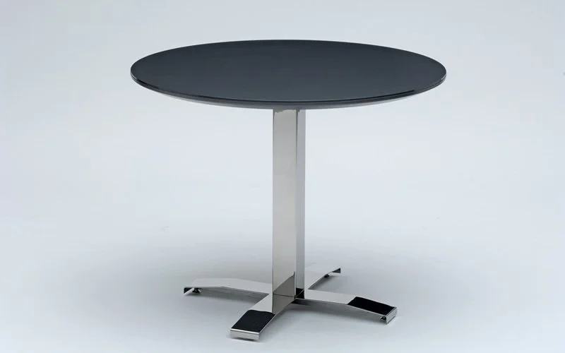 Nextt Cross Base round community table with dark natural stone tabletop and chrome base.