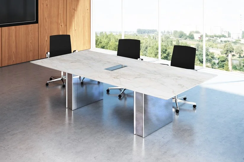 Panel conference room table with a white marble tabletop and a polished aluminum base. Large windows showing a view of green trees and distant buildings.