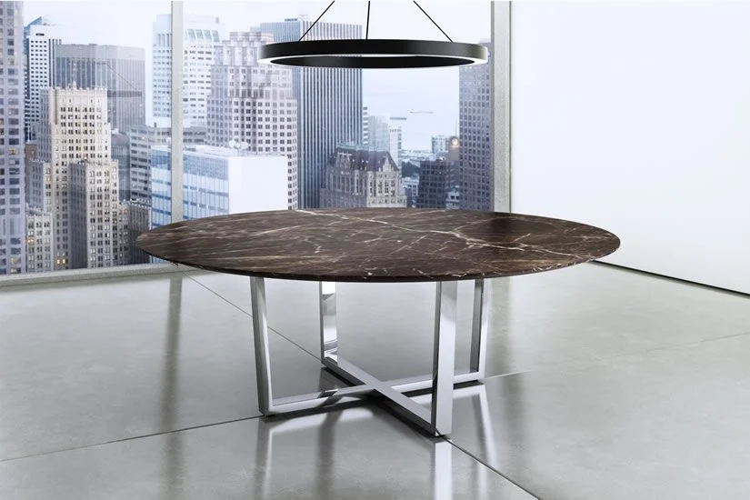 Modern office with a large round marble table and a circular ceiling light, overlooking a city skyline through large windows.