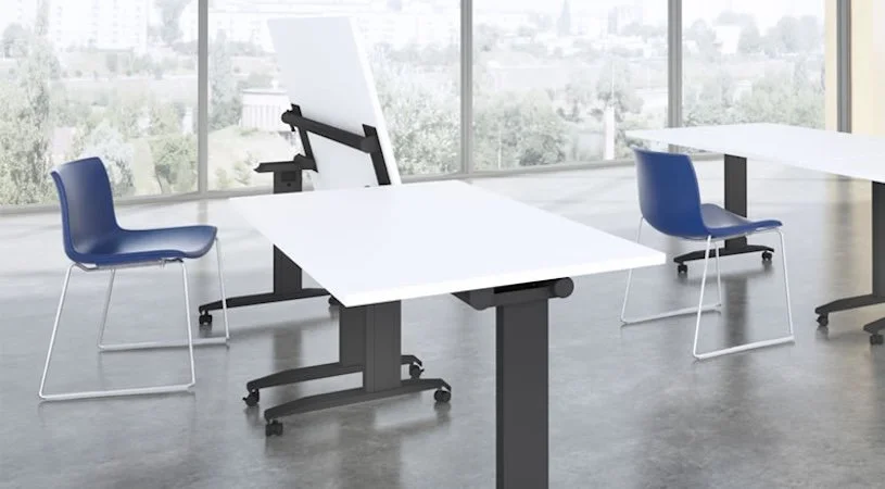 Empty modern office with white desks, blue chairs, large windows, and a city skyline view.