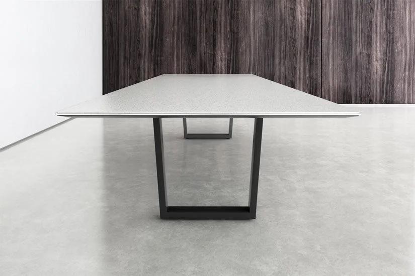 Modern table with white surface and black metal legs in a minimalistic room with gray floor and dark wood wall.