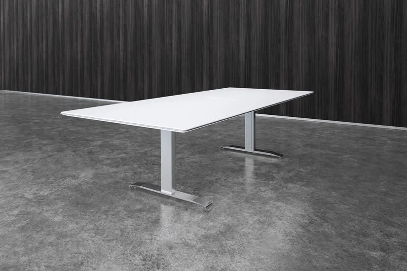 A white office desk with metal legs in a room with a concrete floor and dark wood panel walls.