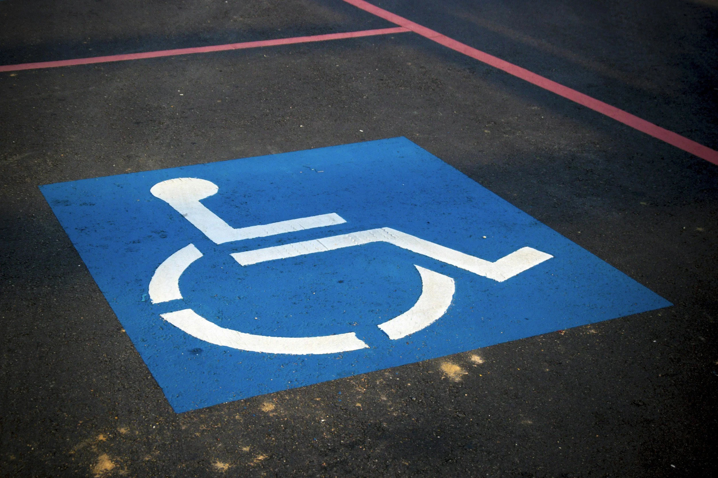 Blue parking space with a white wheelchair accessibility symbol painted on it.