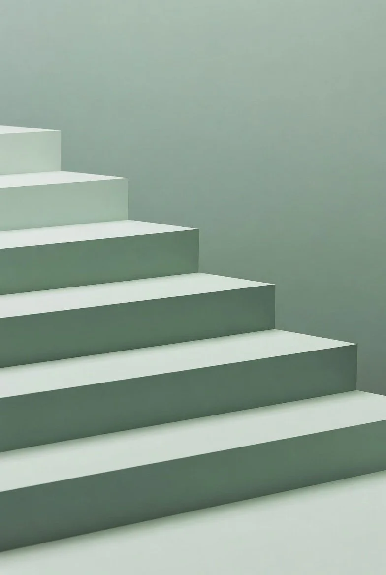 A minimalist staircase with white steps ascending to the left against a pale green wall.