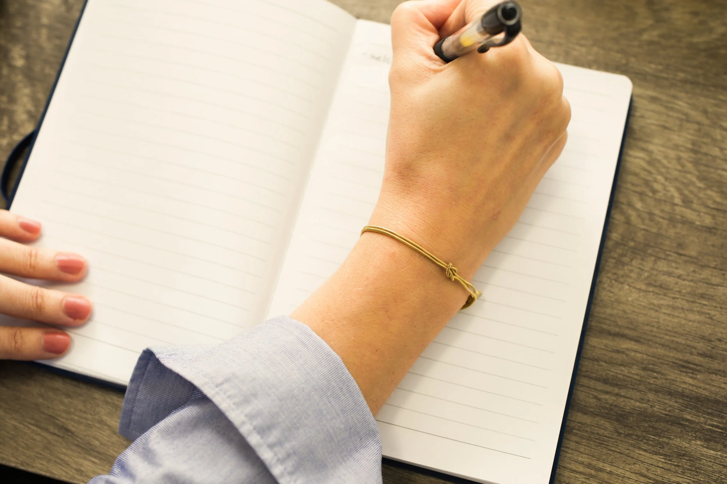 A person writing in a lined notebook, symbolizing the reflective, grounded approach Tara Gogolinski brings to her work as a couples therapist in Raleigh, NC.