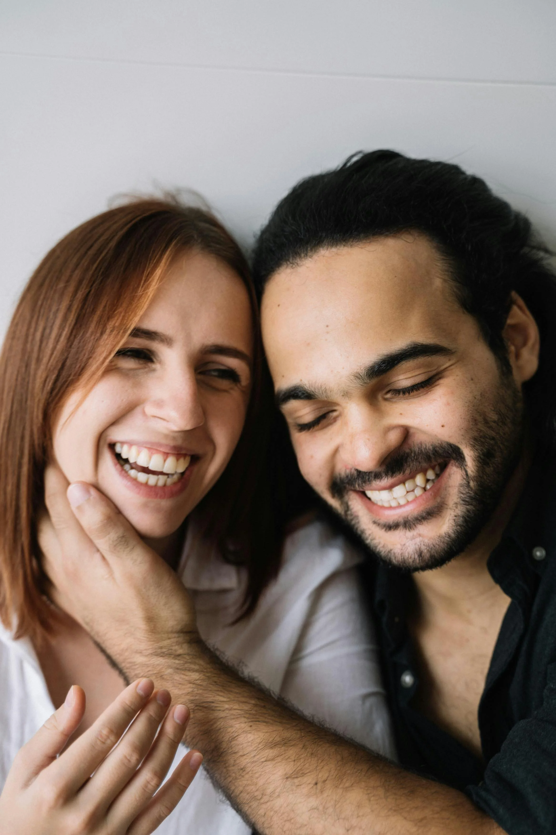A couple sitting closing laughing together after successful couples therapy in raleigh, nc.