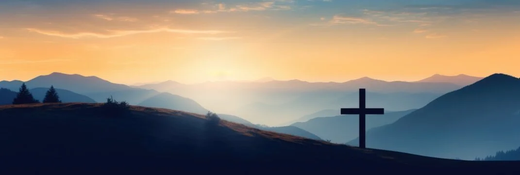 Sunset over mountains with a silhouette of a cross in the foreground.