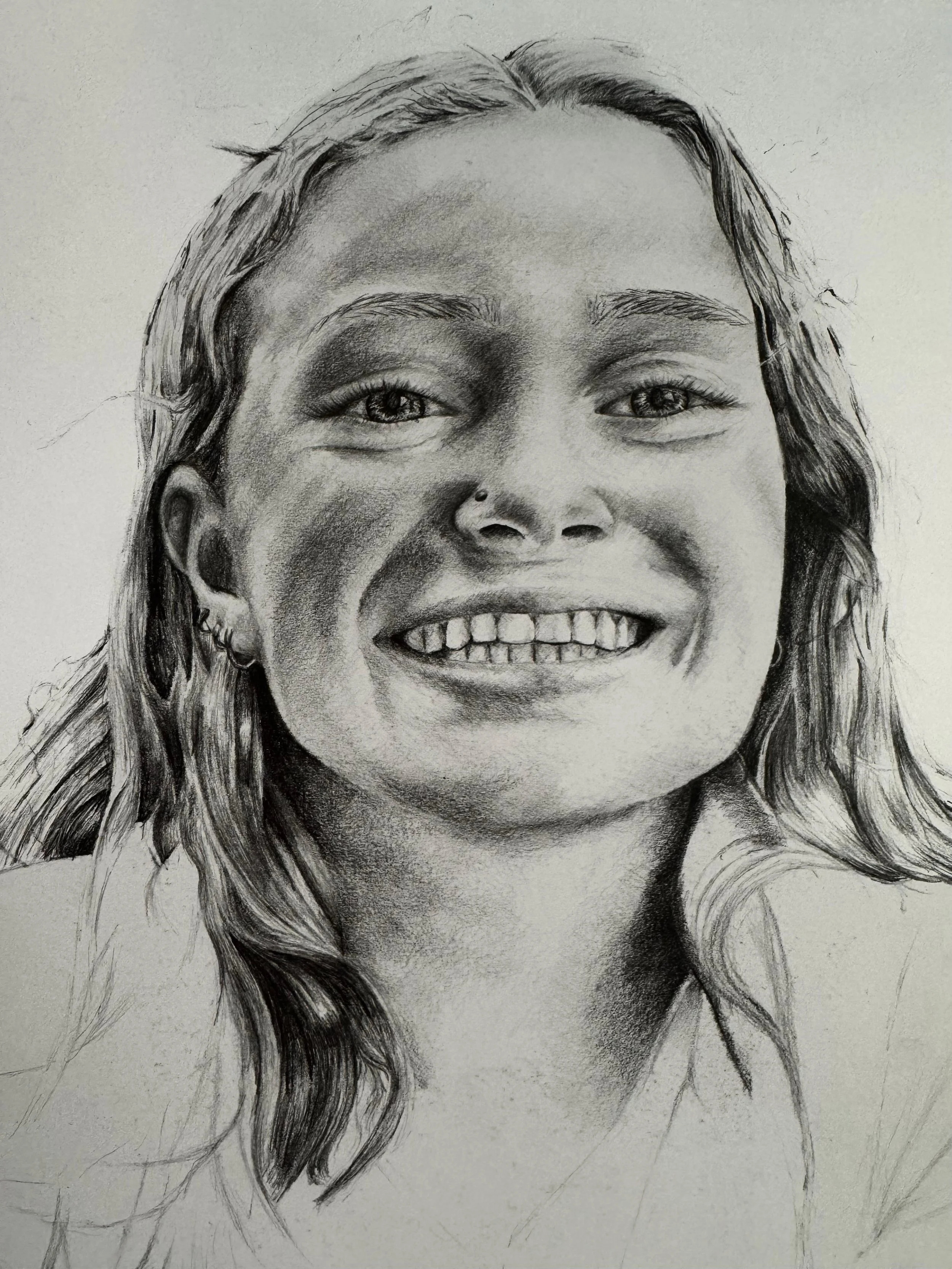 A detailed pencil sketch of a smiling woman with long wavy hair, light skin, and expressive eyes.