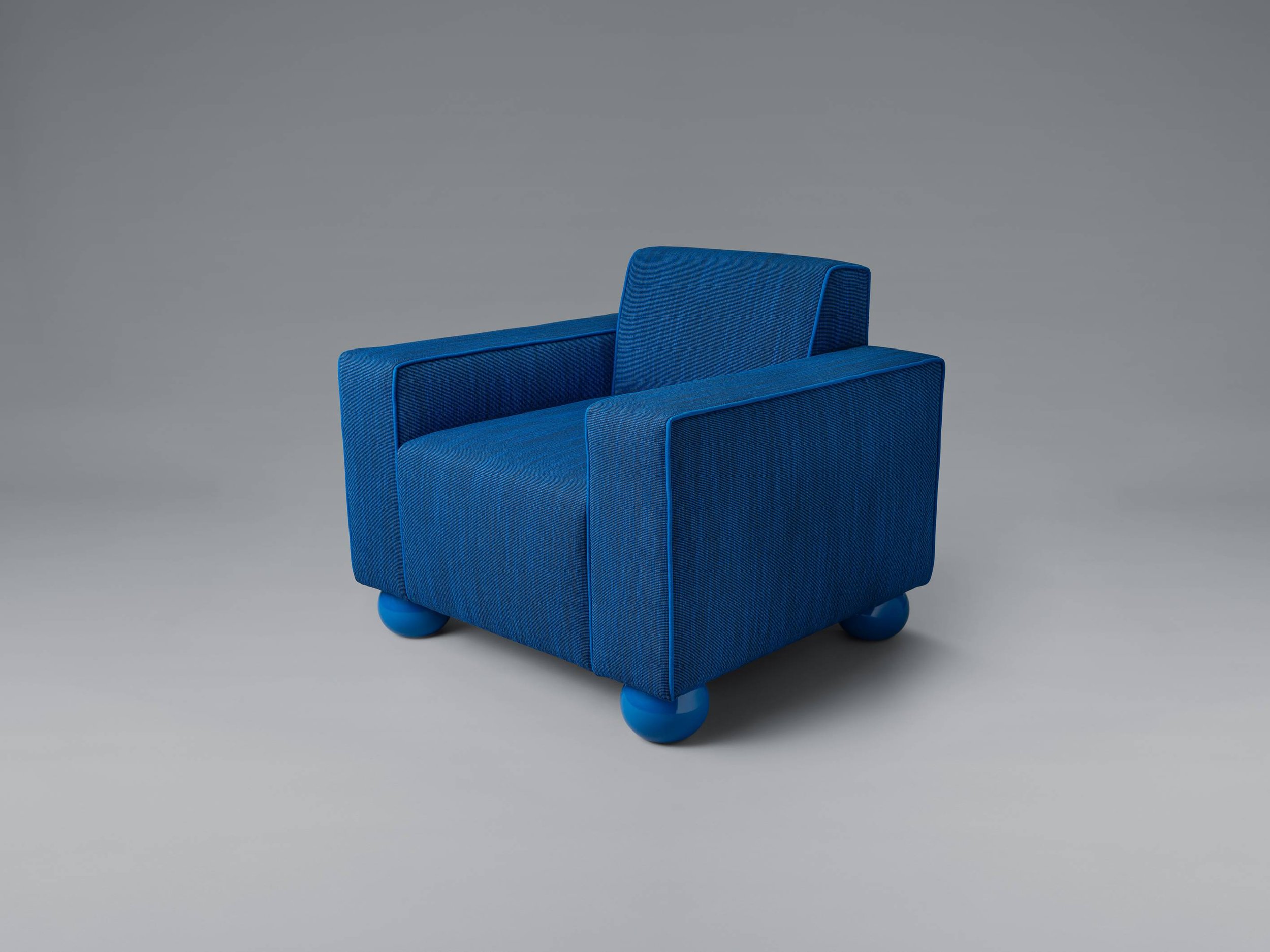 Blue upholstered armchair with rounded blue legs on a gray background.