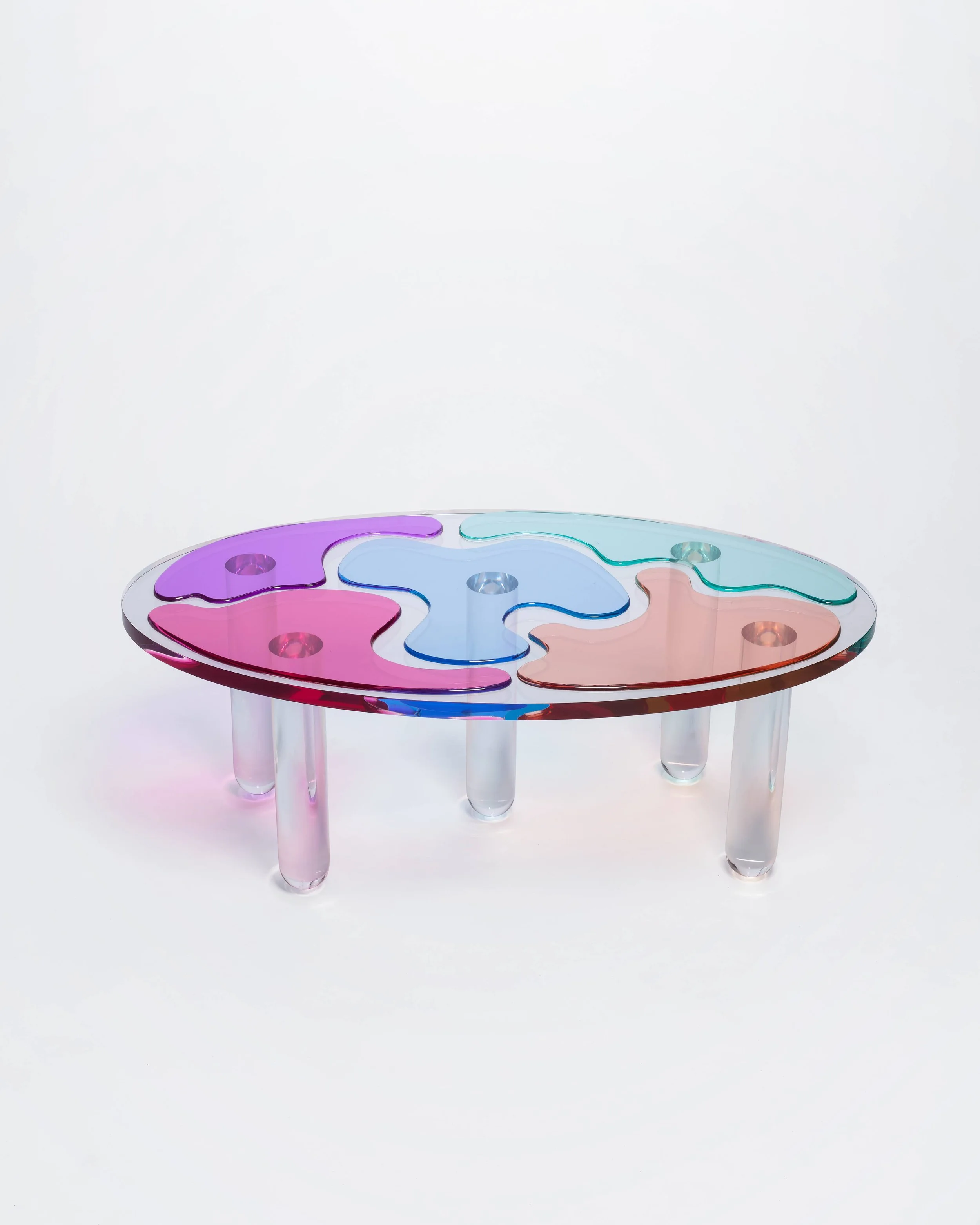 Colorful puzzle piece table with a clear plastic base, set against a plain white background.