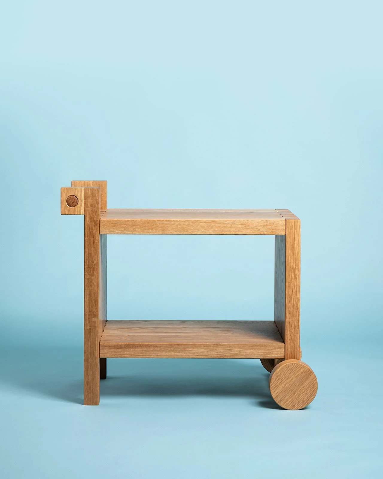 Minimalist wooden cart with two wheels on a light blue background.