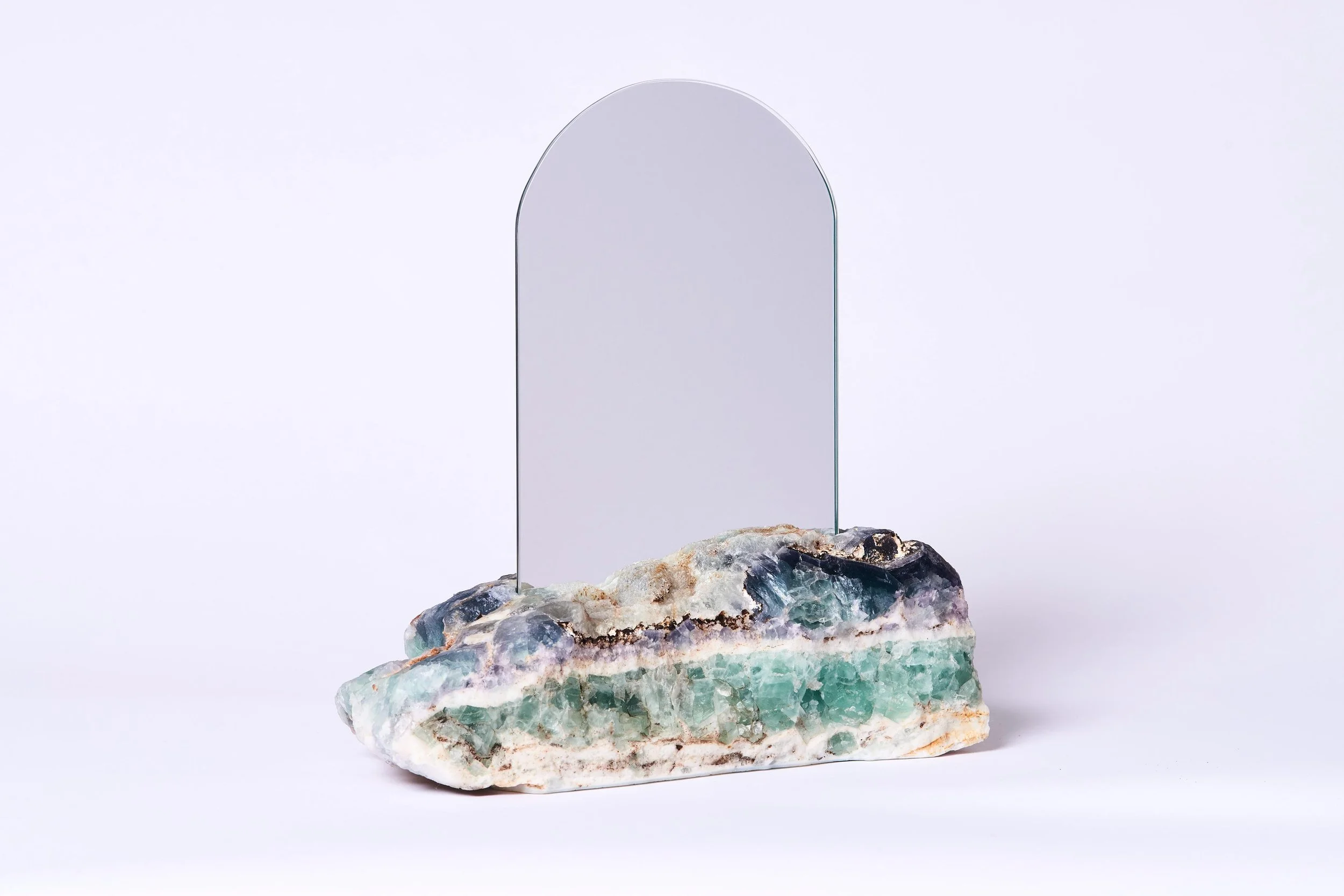 A decorative stone base with a mirror standing behind it on a white background.