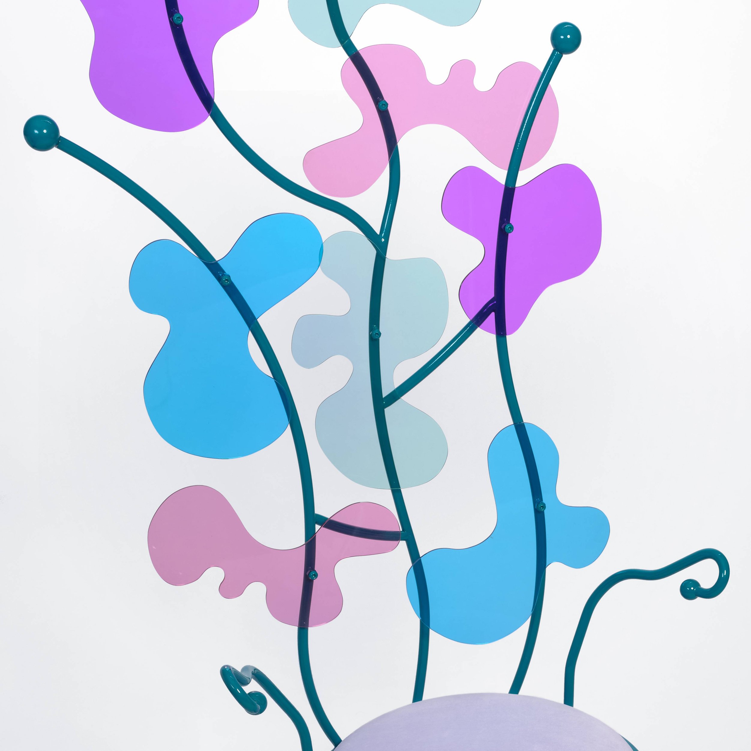 Abstract colorful art piece with curved teal metal branches, translucent pink, blue, and purple shapes resembling leaves or petals, against a white background.