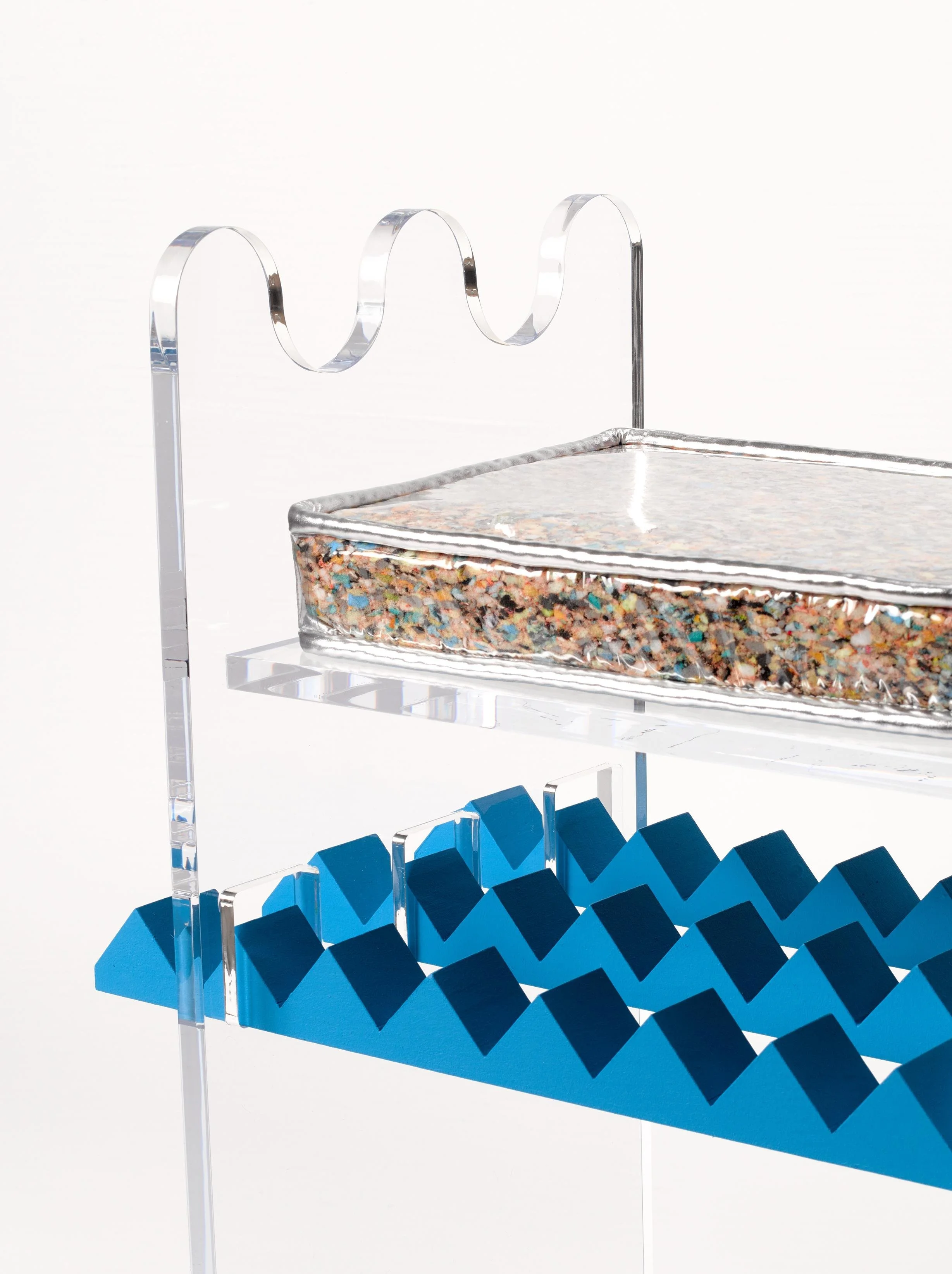 An abstract modern sculpture with clear acrylic, colorful terrazzo, and blue geometric elements.