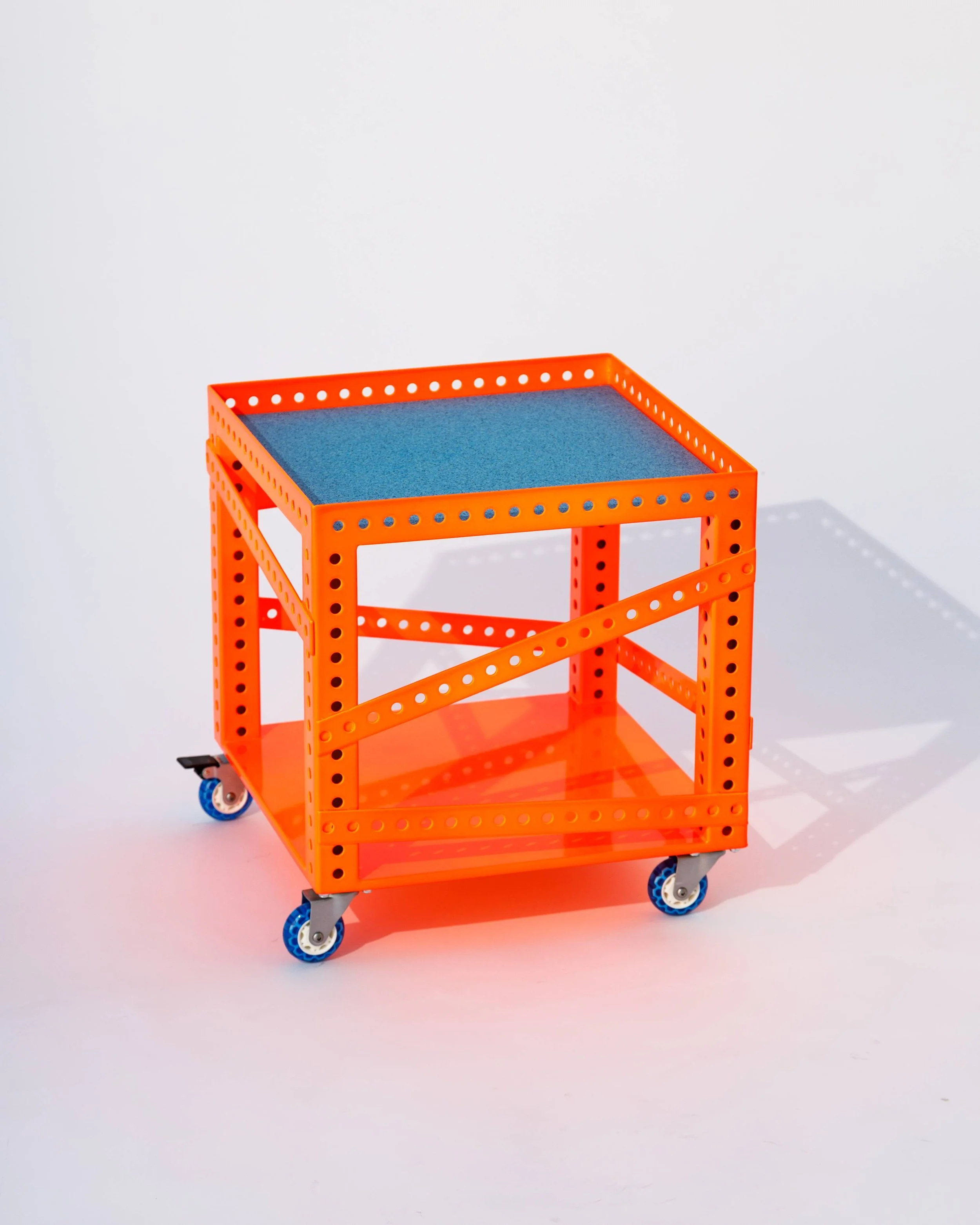 Orange metal rolling cart with a blue shelf on top and a mesh shelf below, against a white background.