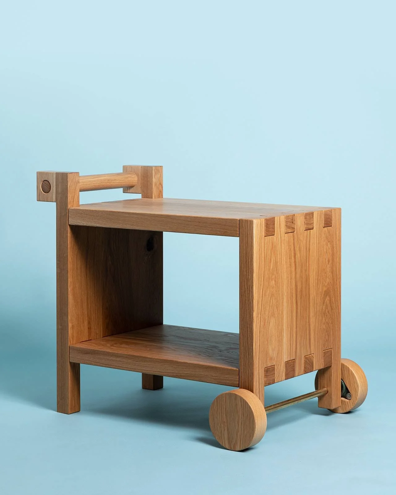 Wooden child's toy cart with wheels against a light blue background.