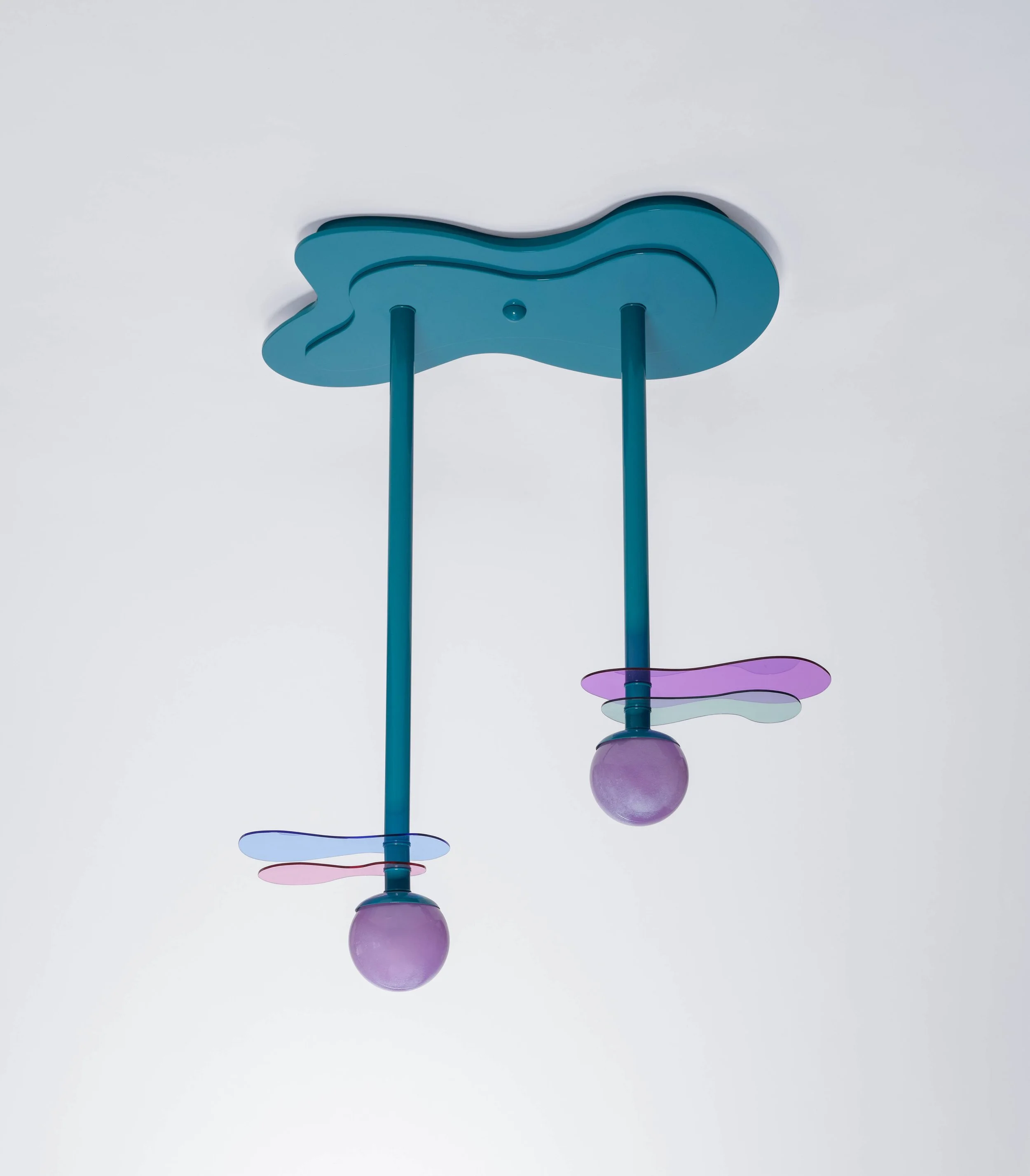 Colorful ceiling light fixture with two blue rods, purple globes, and pastel-colored decorative elements on a white ceiling.