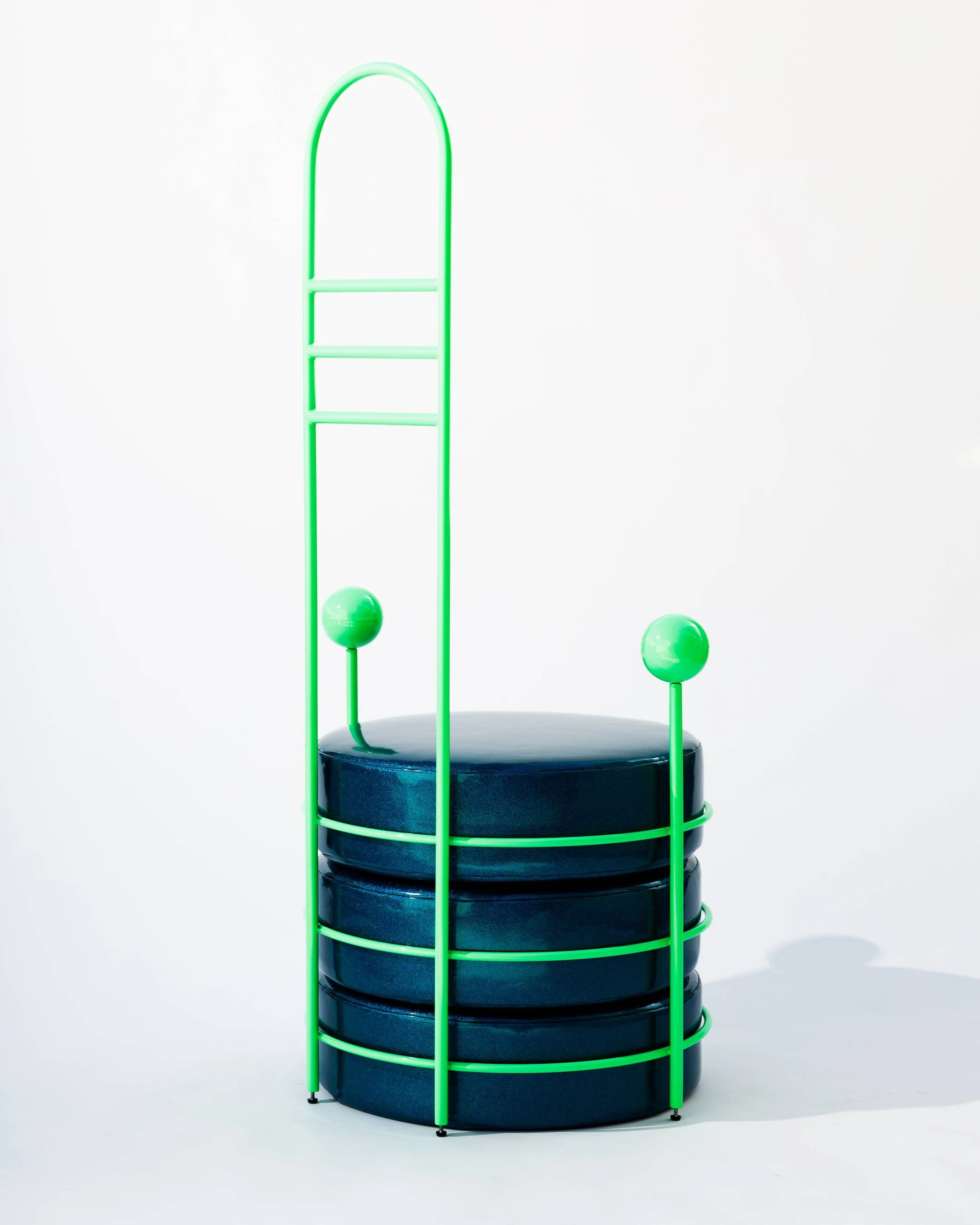 A modern stack of black round cushions with neon green metal frame and decorative orbs, against a plain white background.