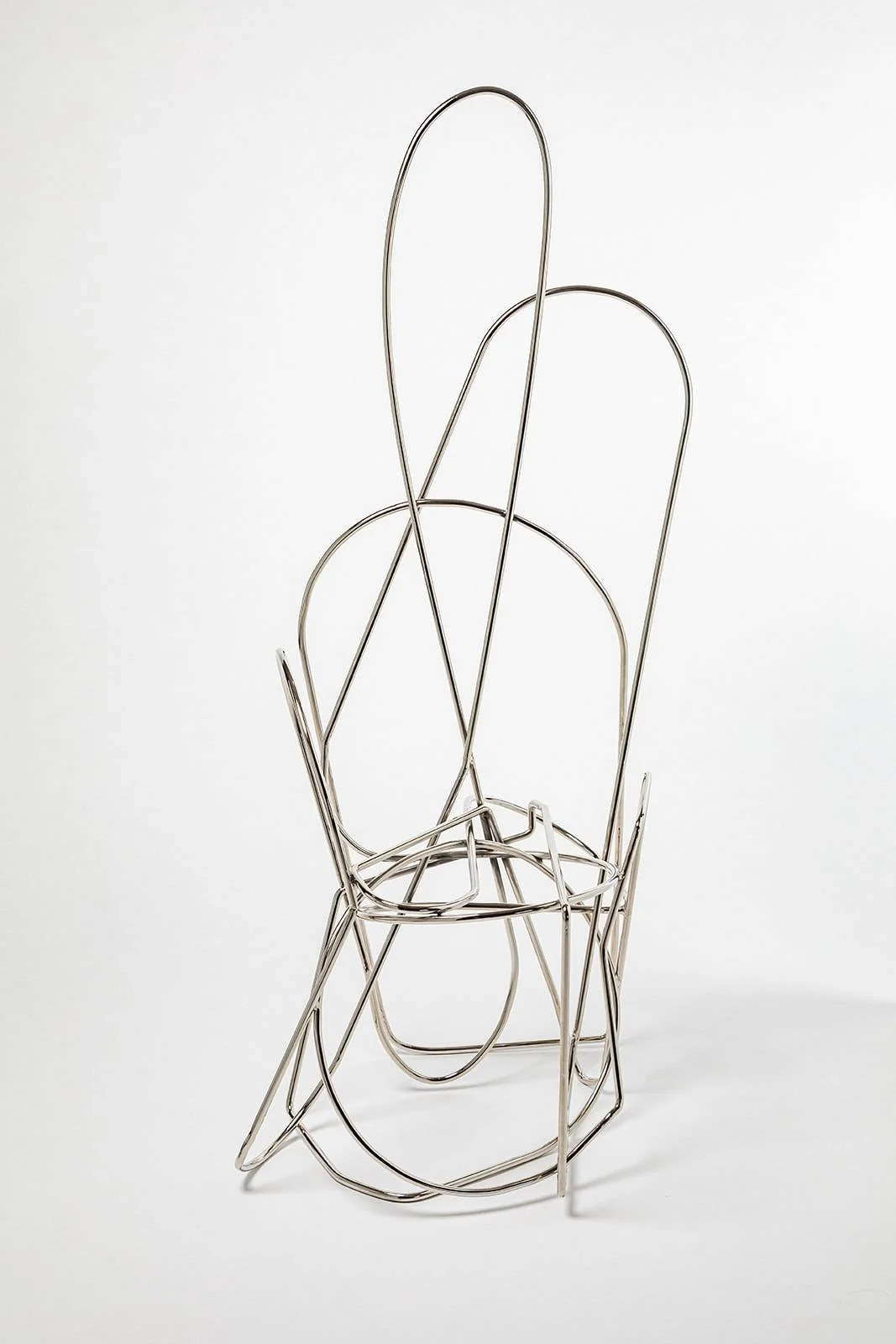 A modern, silver wire sculpture of a chair with abstract, minimalist design.