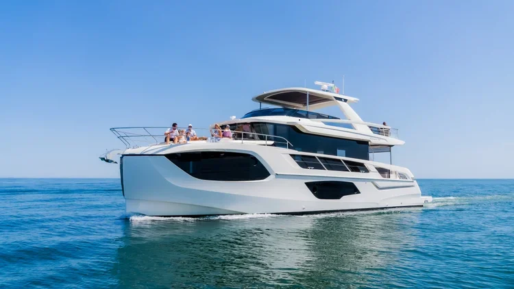 A large white Absolute Navetta yacht sailing on the ocean with people on the deck.