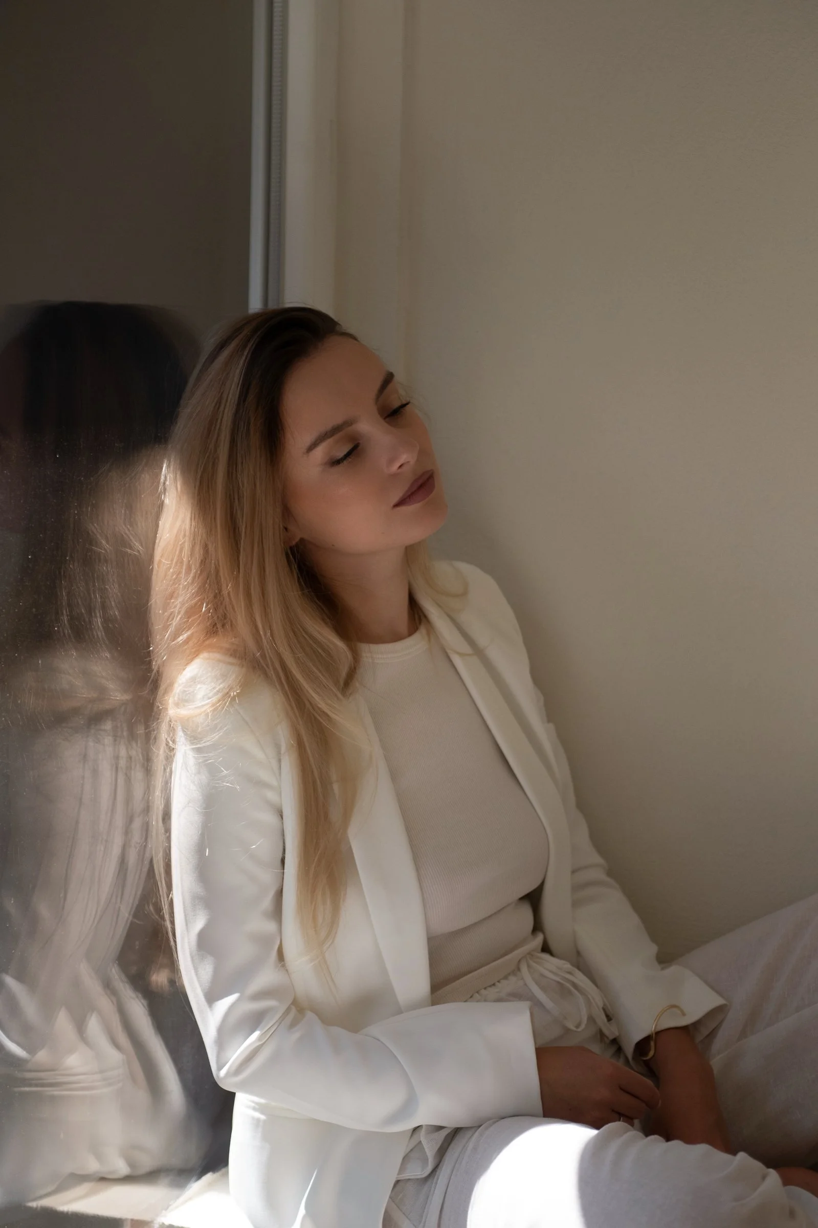 Dr. Trish Schneider, functional medicine coach and psych NP, leaning on mirror in calming neutral space