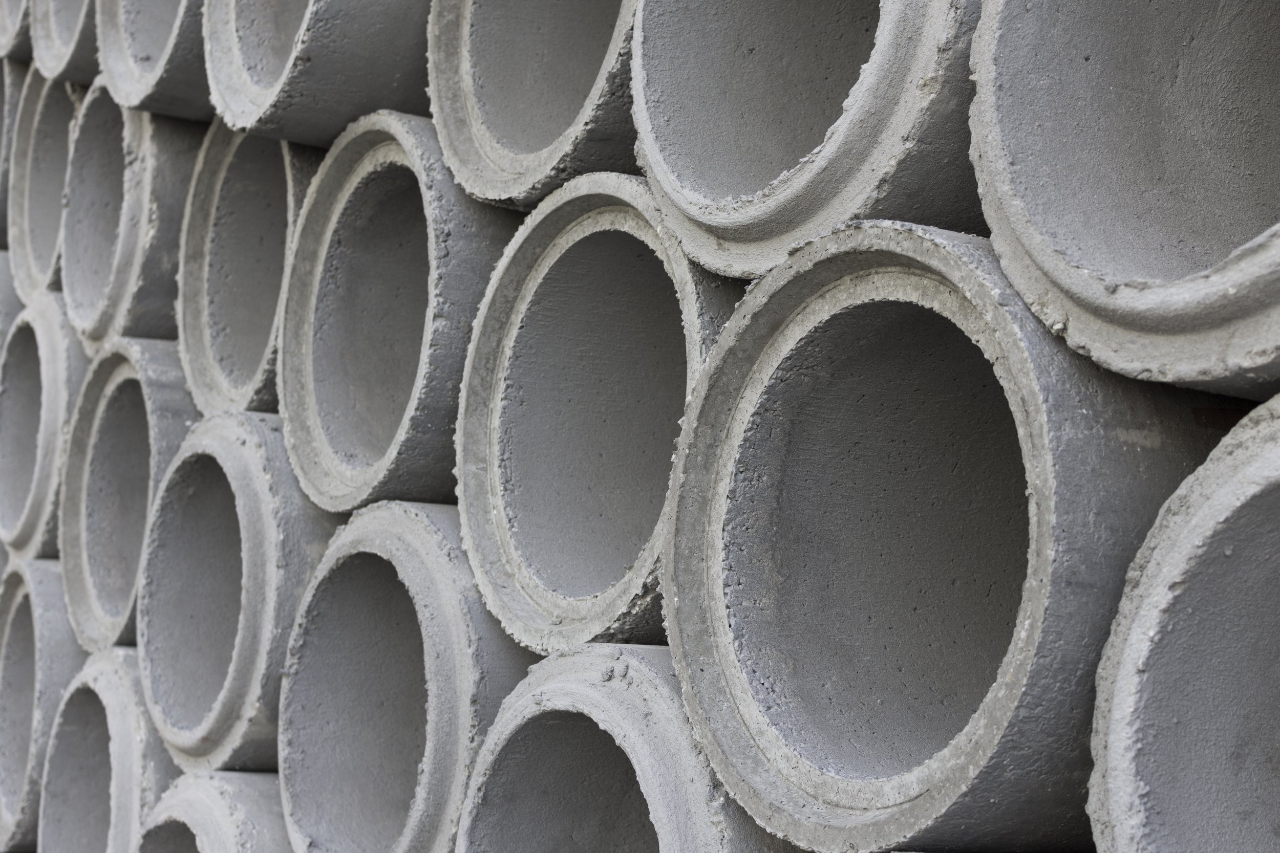 Stack of concrete pipes arranged in a pyramid pattern.