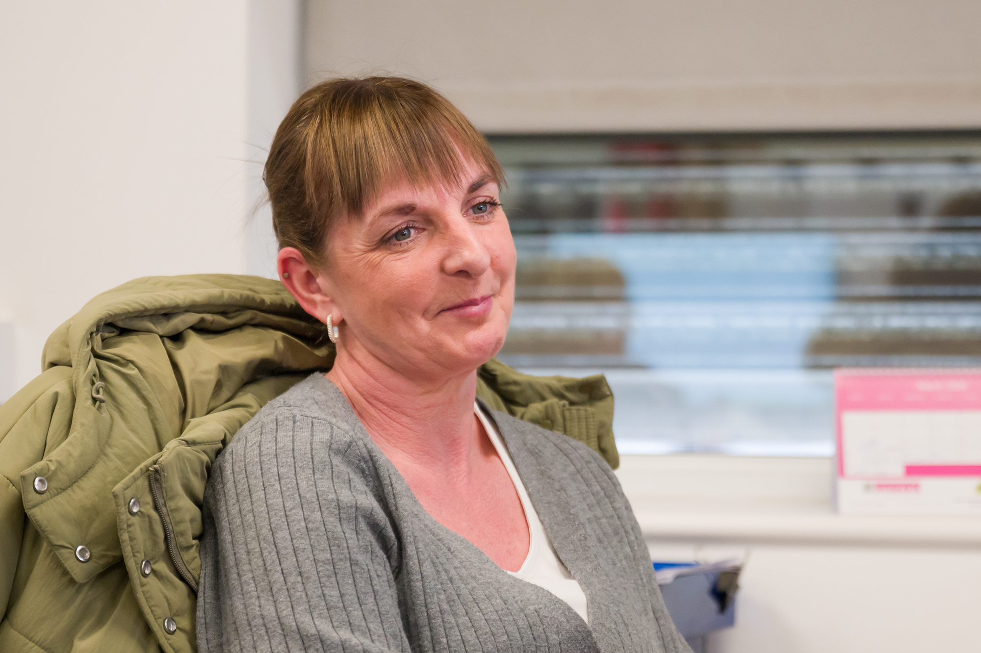 Female office st5aff wearing a grey carigan smiling and looking away from the camera.