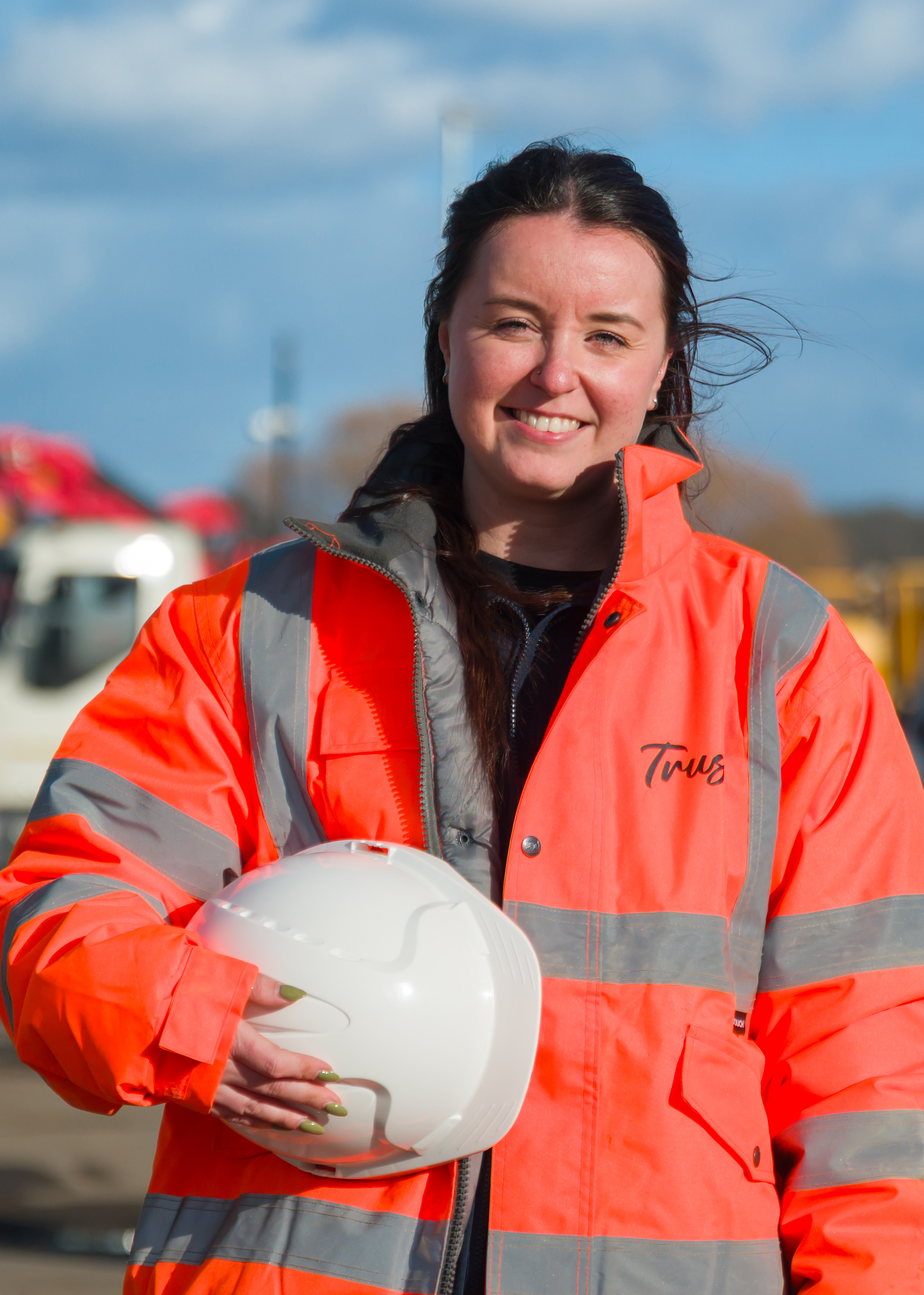 Female worker on site in orange hi-vis Trust branded clothing