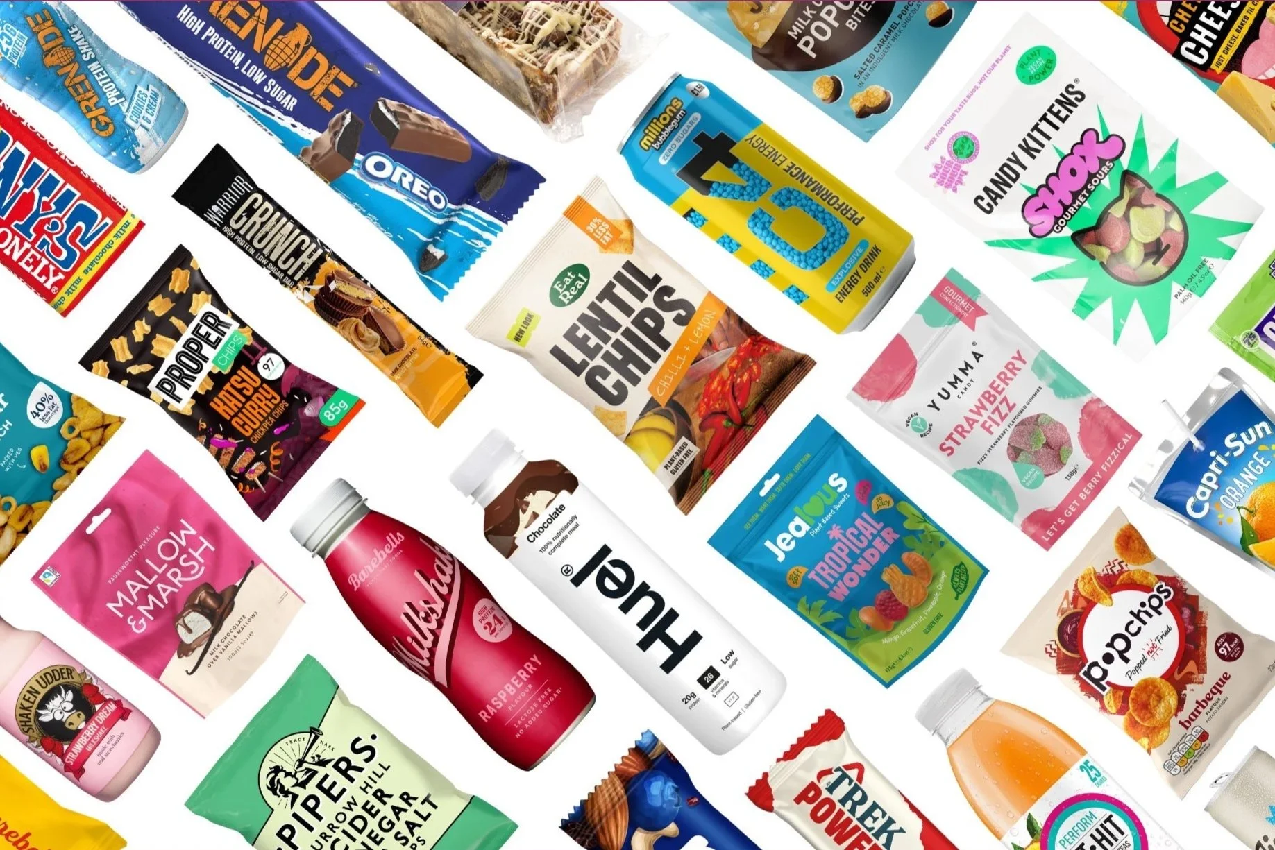 Assorted snack and beverage packages scattered on a surface, including chips, biscuits, candies, and drinks.