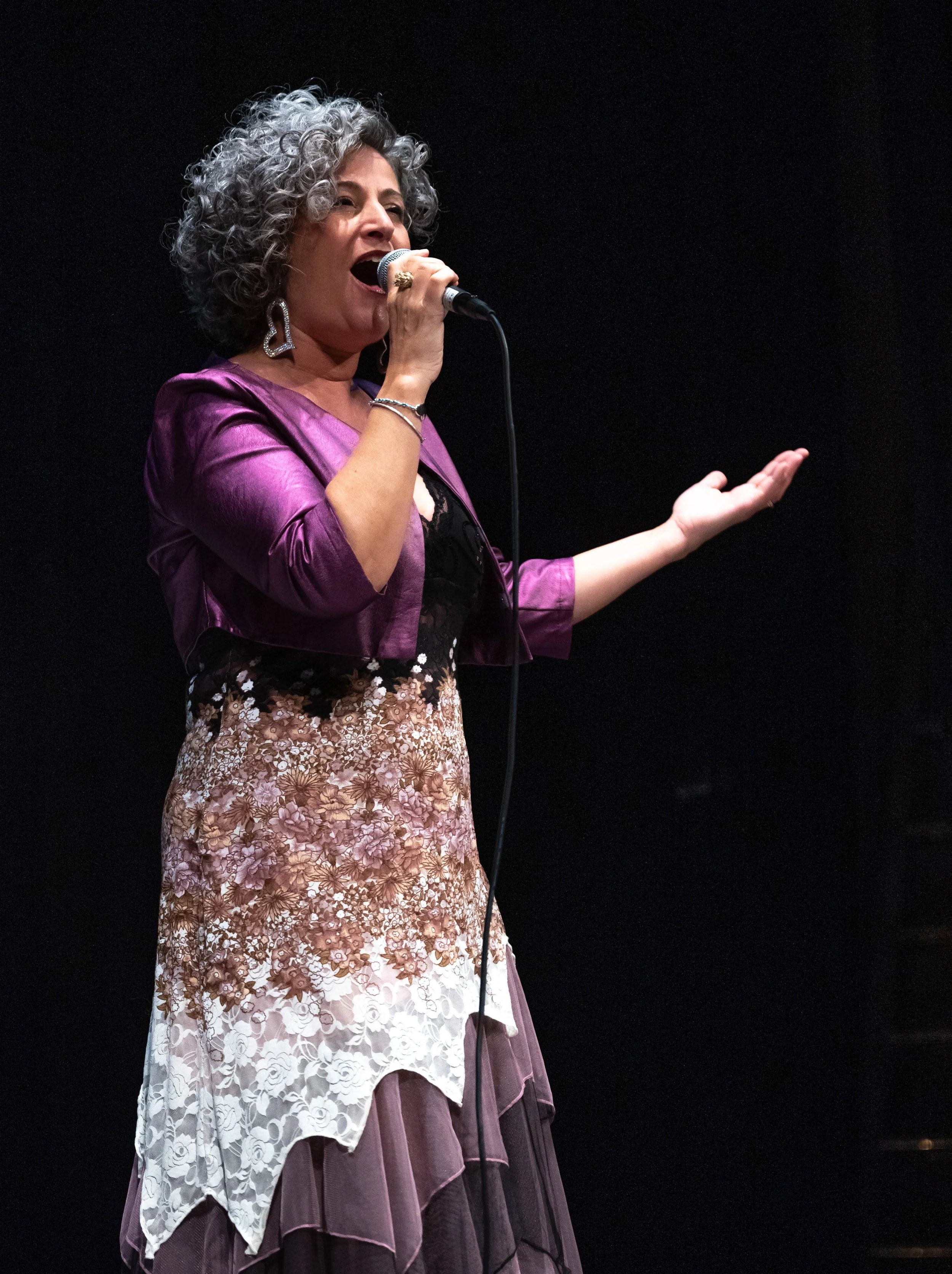 Anna Chiara Farneti che canta con microfono su sfondo nero.