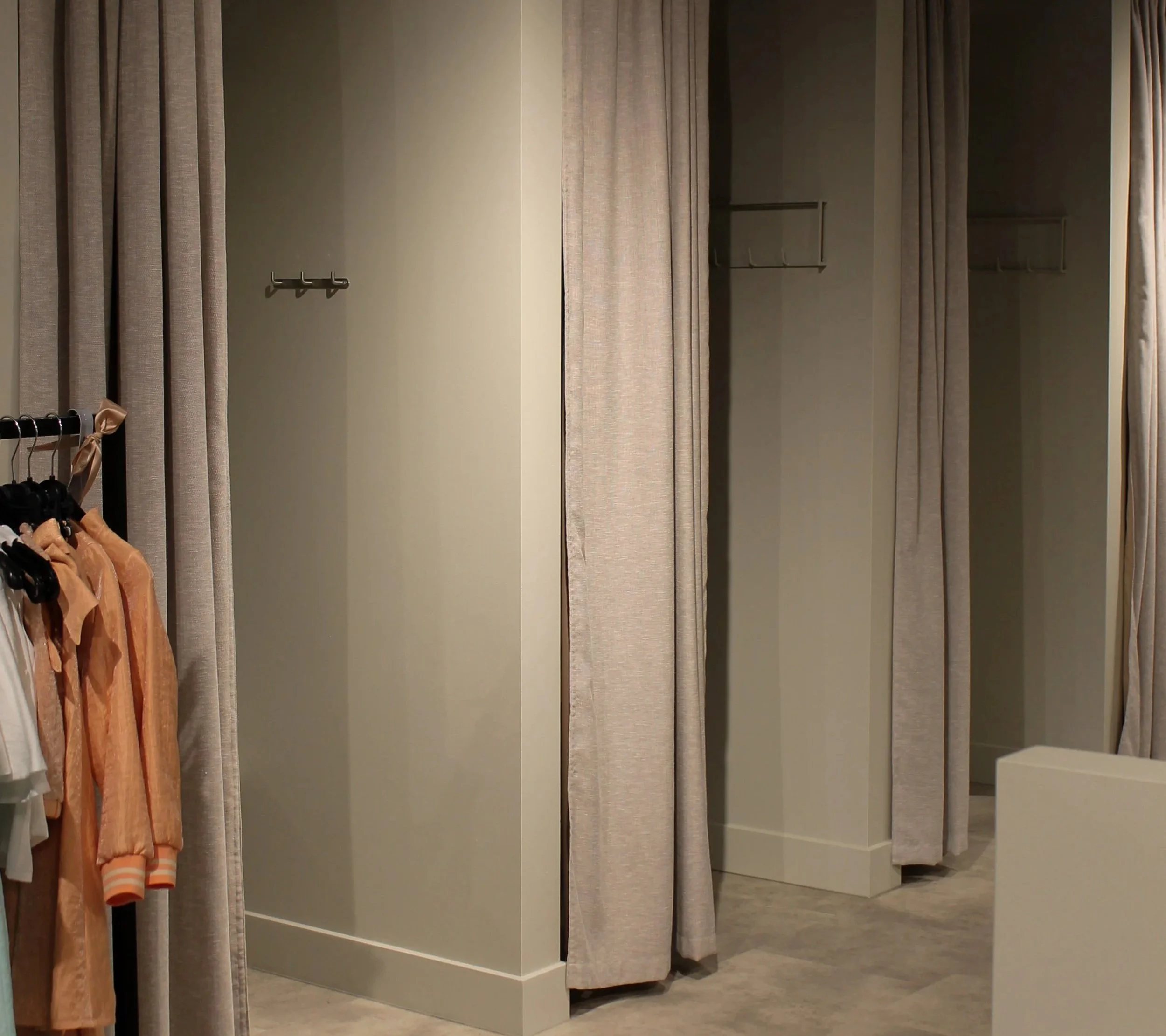 Lege paskamer met beige gordijnen en een kledingrek aan de linkerkant.