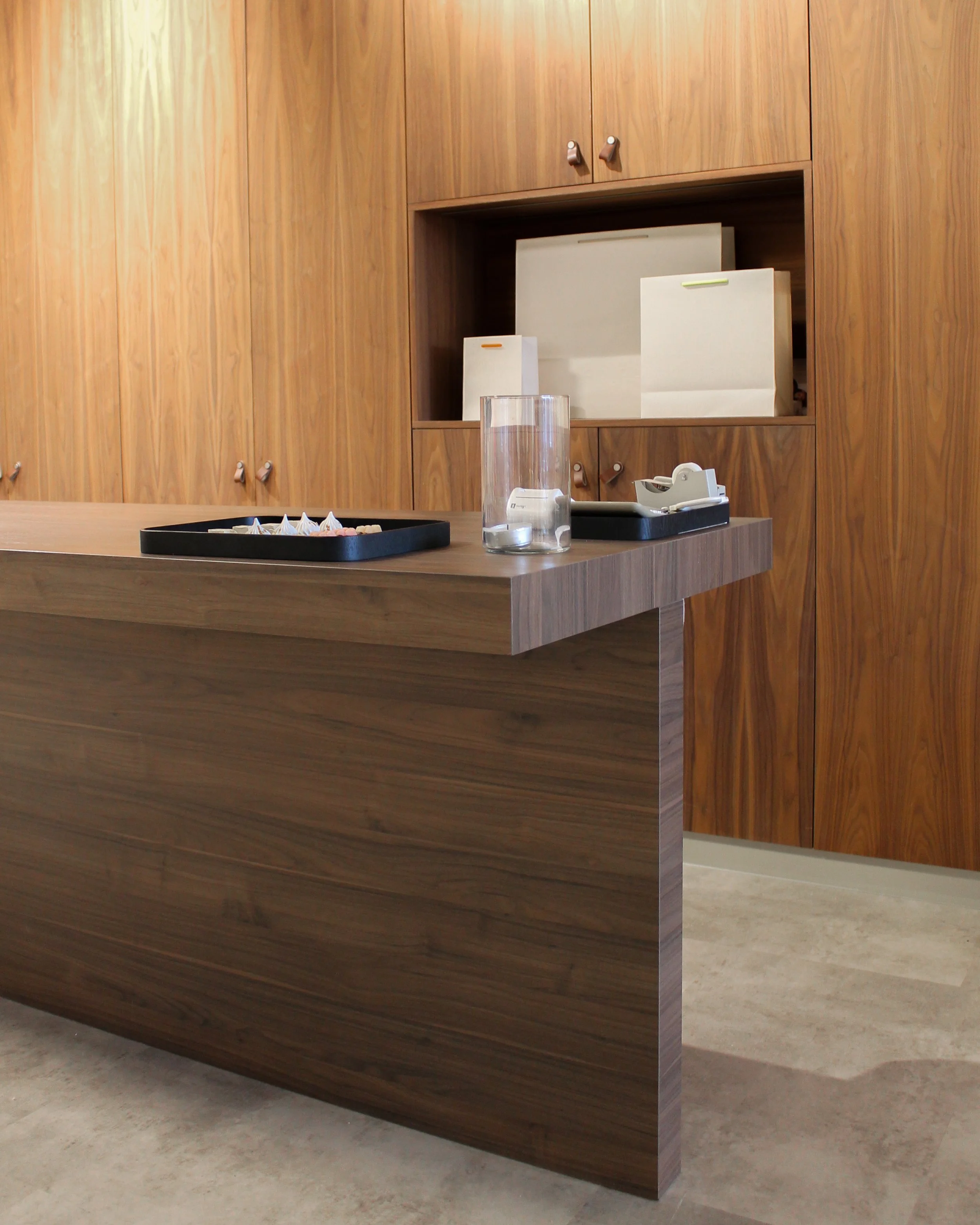 Houten receptiebalie tegen een houten wand met opbergkasten.