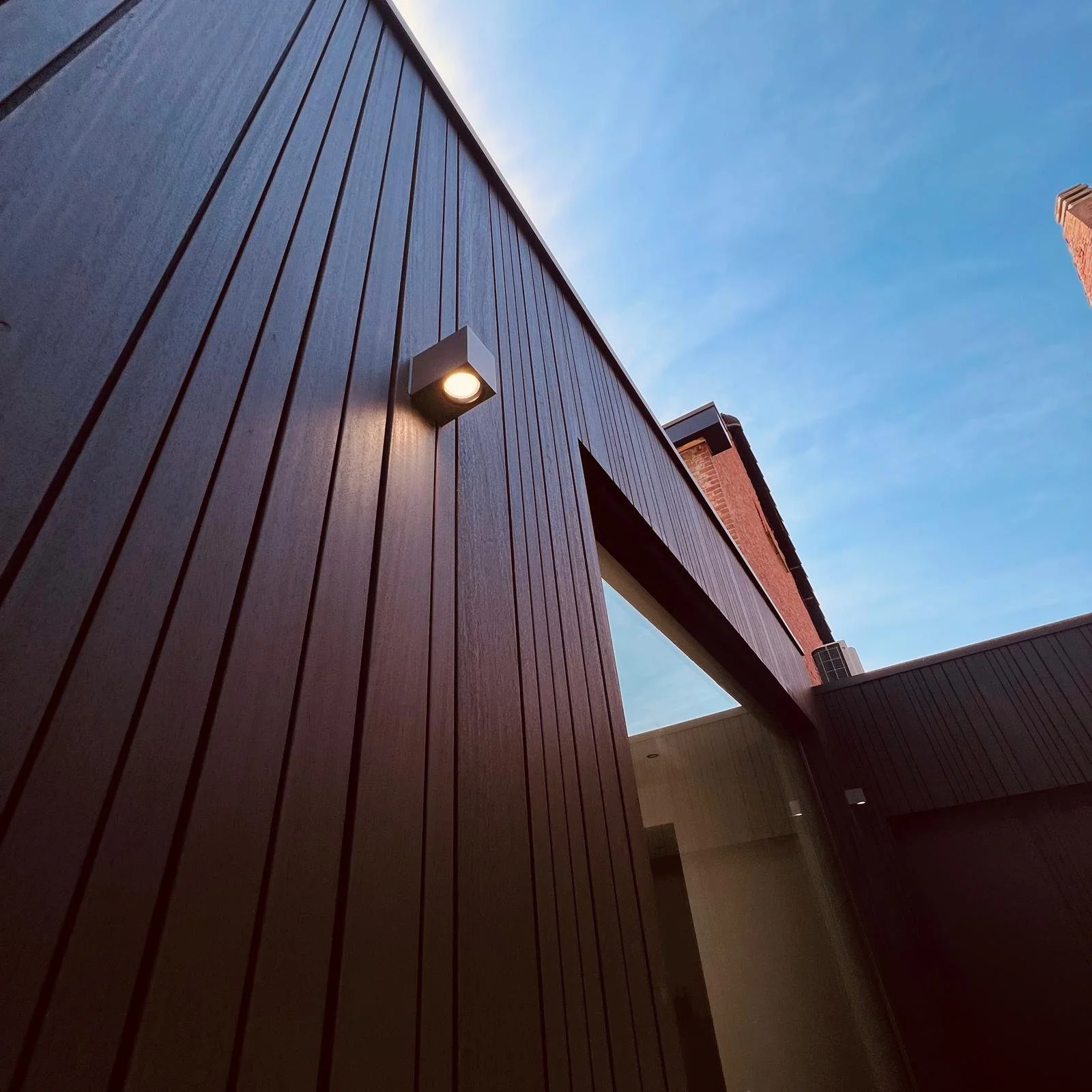 Modern gebouw met een zwarte buitenkant en een blauwe lucht op de achtergrond.