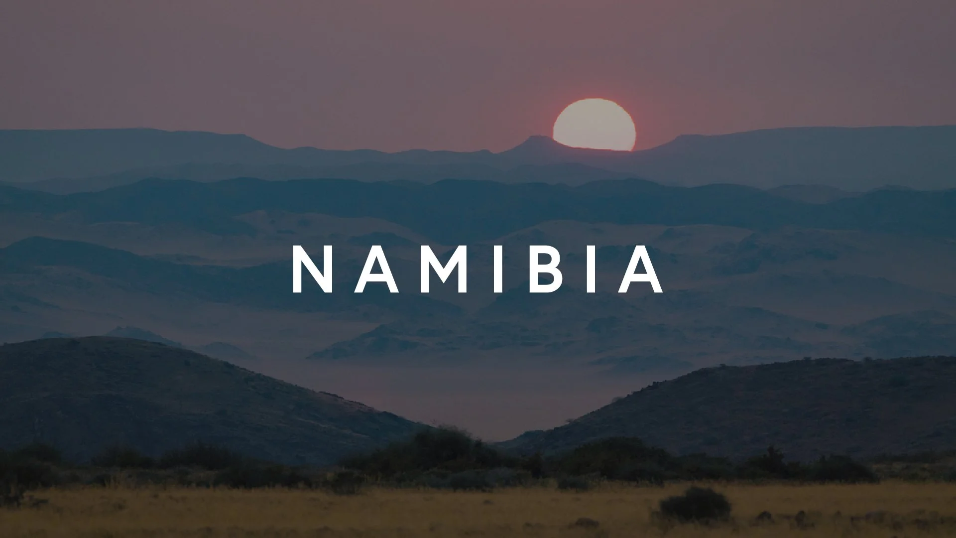 Scenic view of mountains with a setting sun and the word 'Namibia' overlaid
