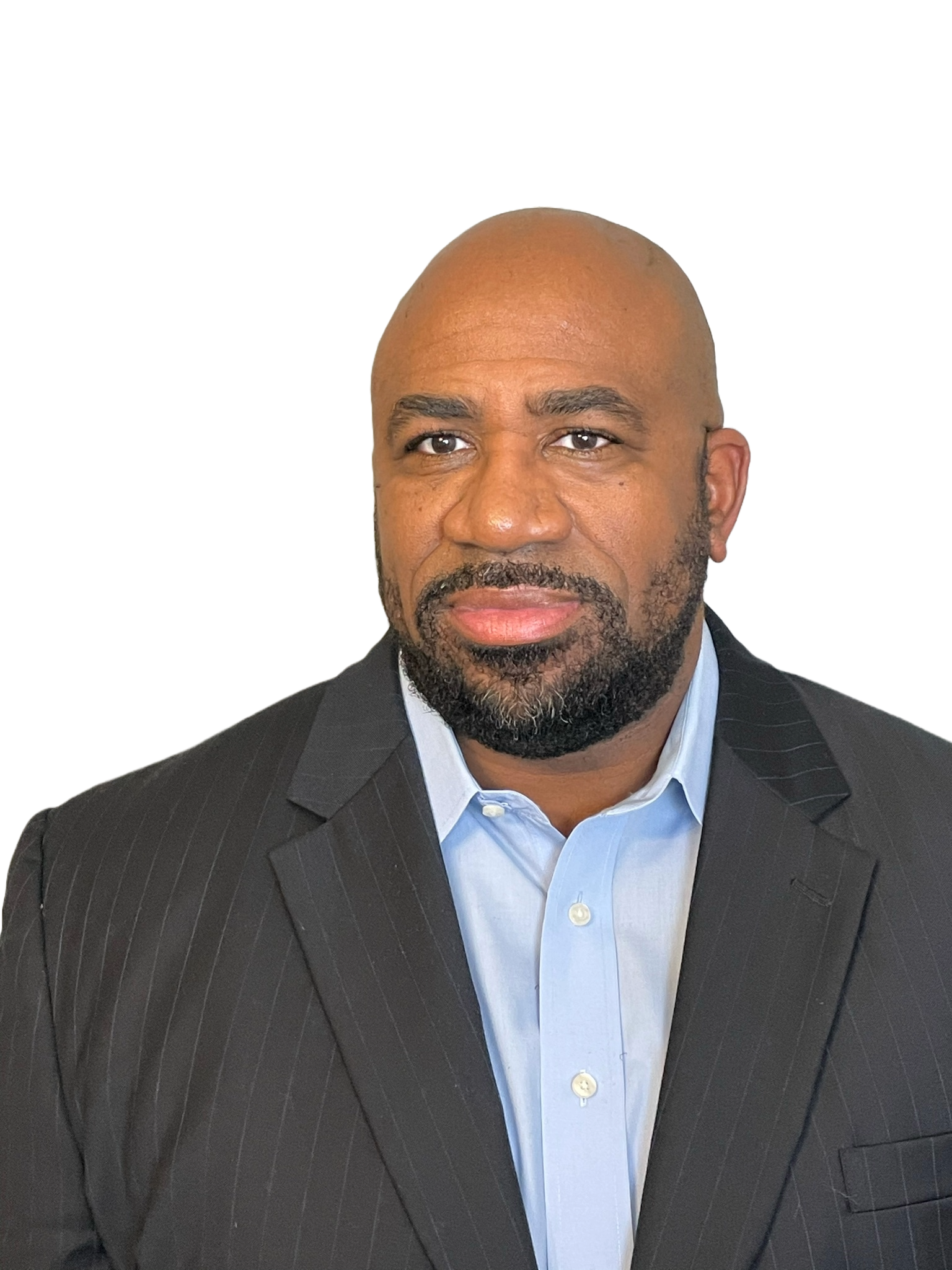 A man with a dark beard and a bald head, dressed in a black pinstripe suit and light blue shirt, looking directly at the camera.