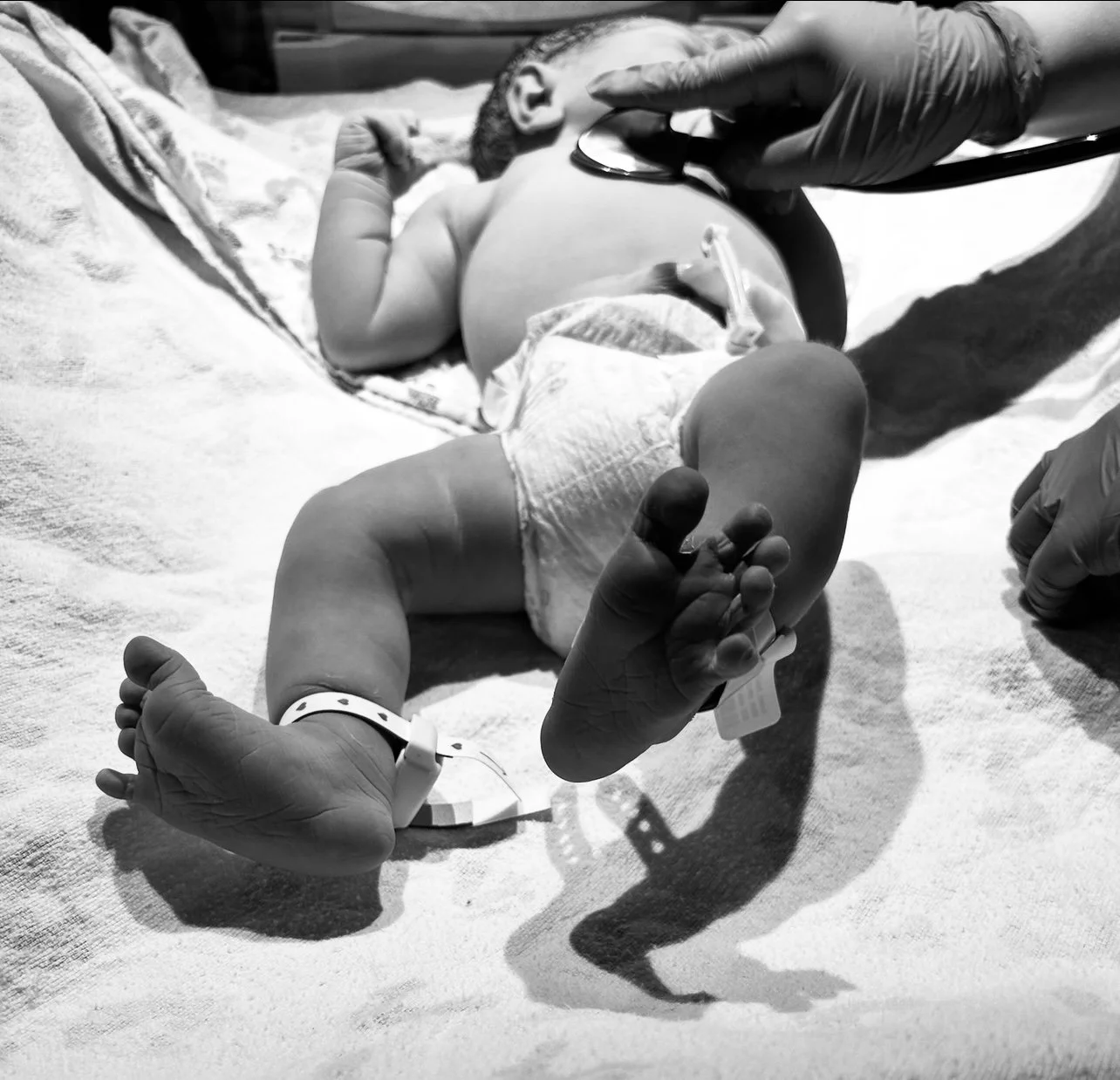 Newborn baby moments after birth being gently checked by a nurse in a hospital setting, supported by a birth doula providing calm, informed care to families in Central Texas