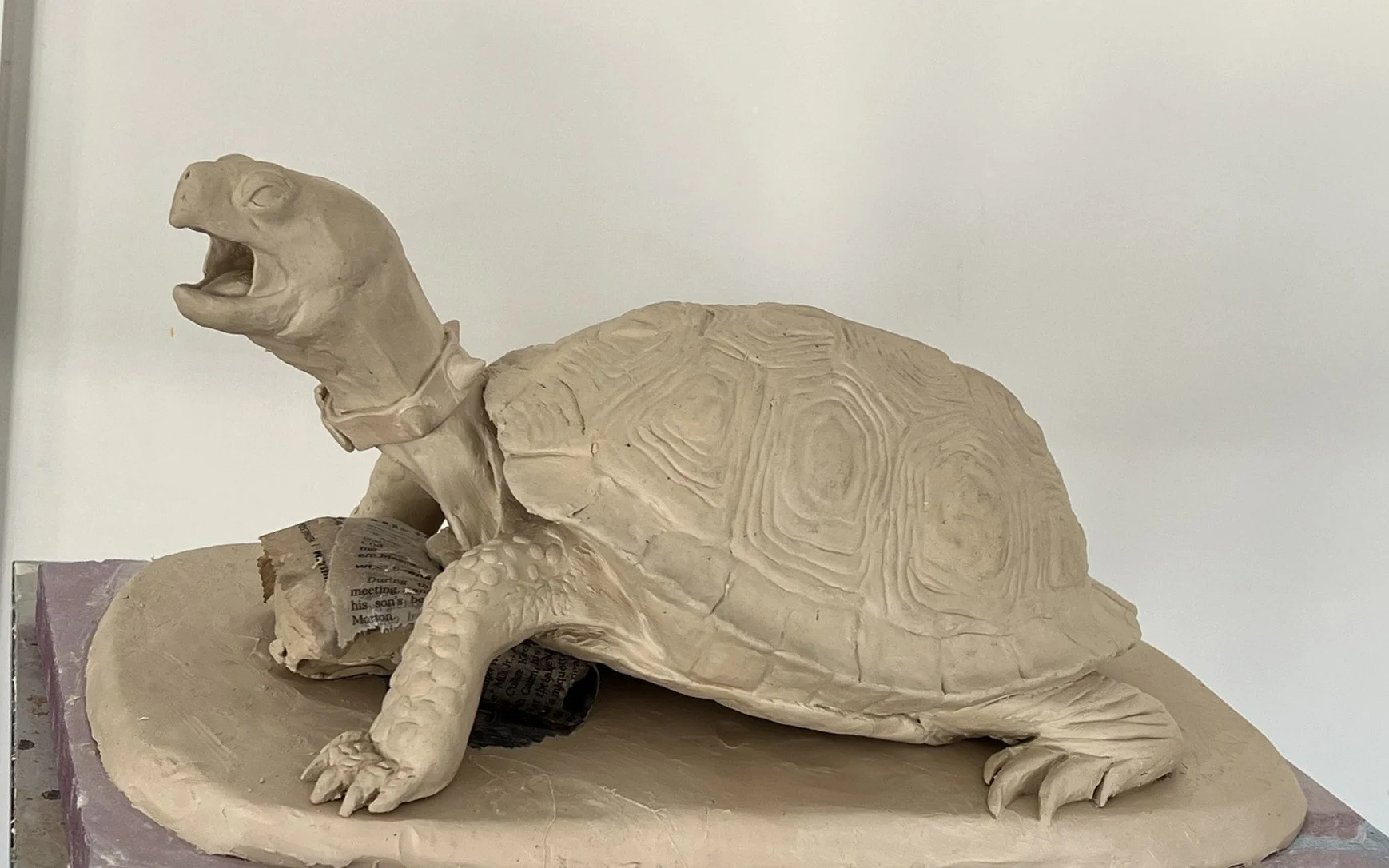 A clay sculpture of an Eastern Box Turtle with a studded collar around his neck and barking like a dog