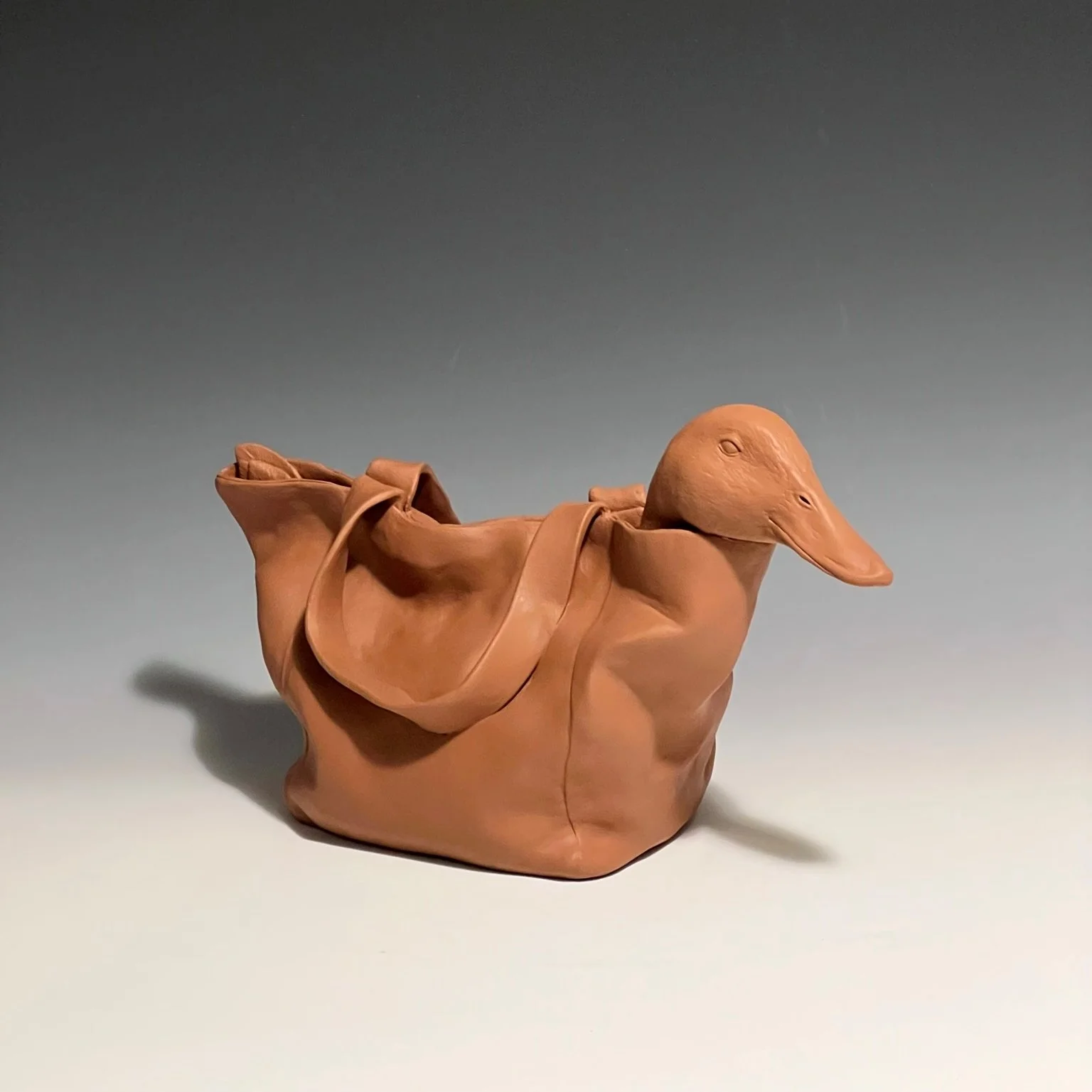 A sculpture of a mallard duck peeking from a cloth bag
