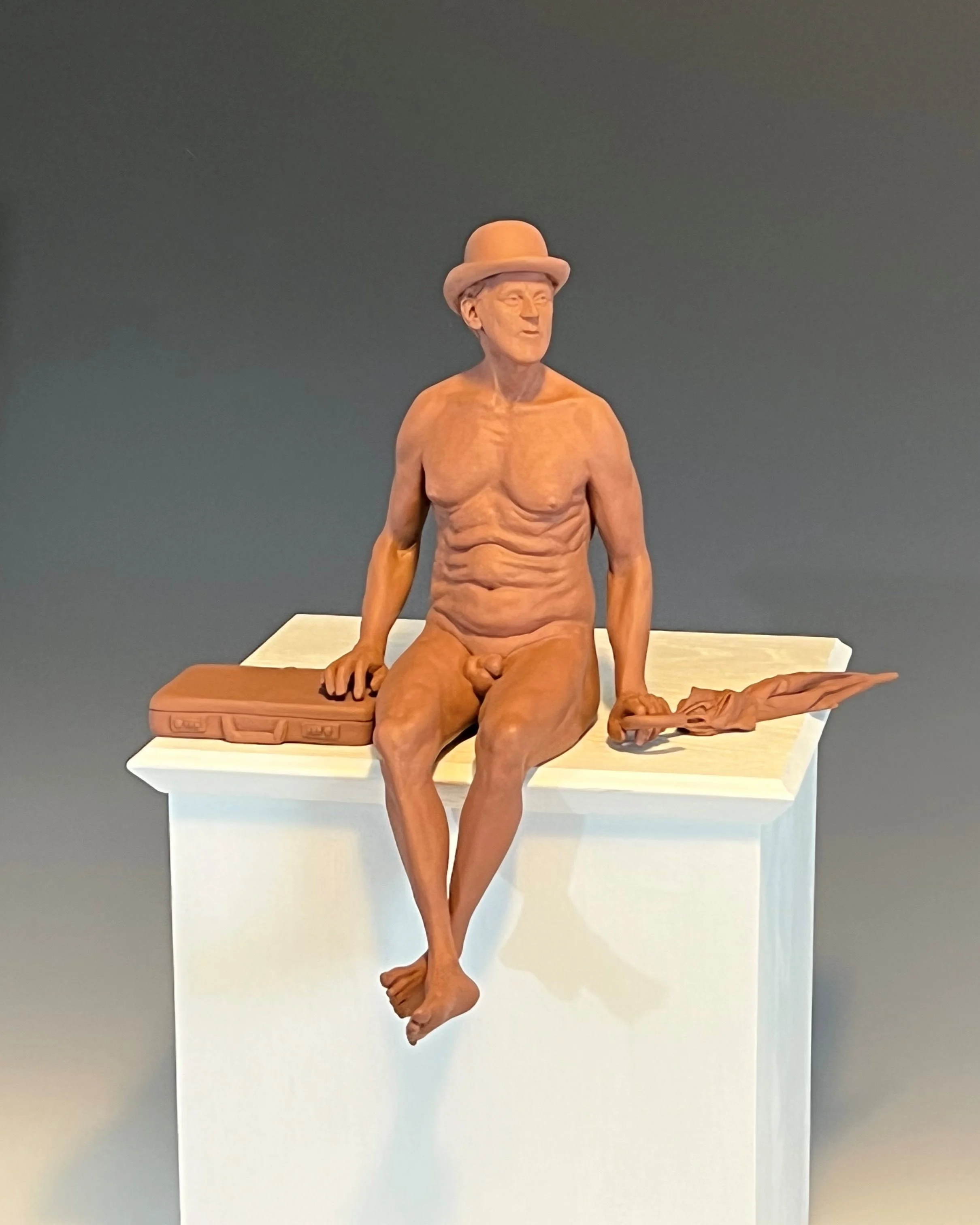 Sculpture of a naked man wearing a bowler hat and sat with a briefcase and umbrella
