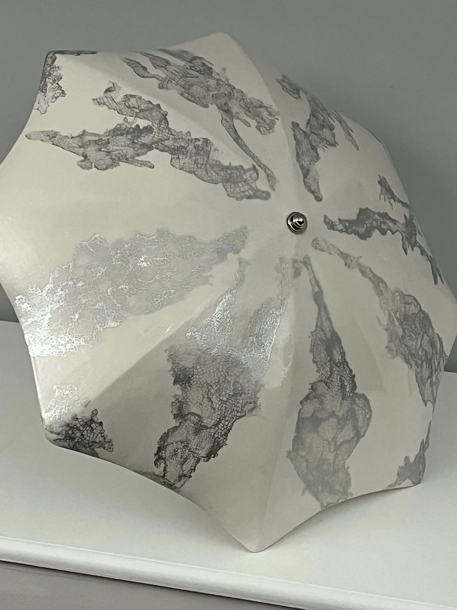 Large white ceramic umbrella with a crazed silver metallic glaze pattern through it