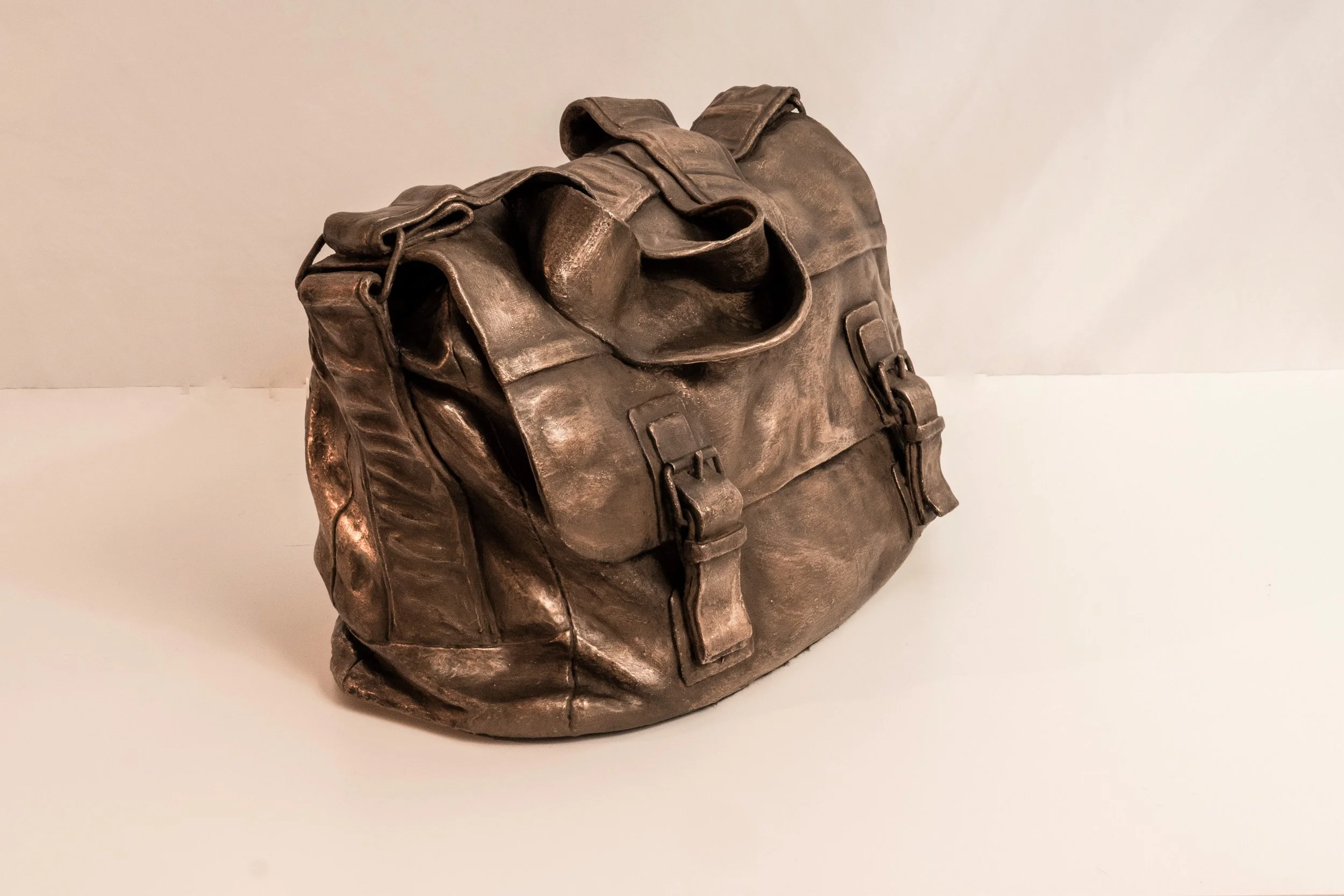 Bronze finished ceramic sculpture of a leather bag with high level of folding detail