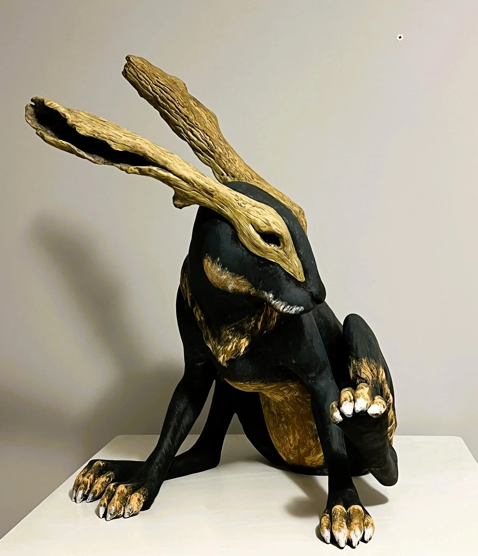 Ceramic hare sculpture with wooden ears and a smoldering tail