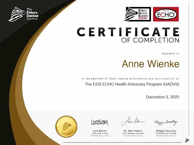 A certificate of completion awarded to Anne Wienke for the EDS ECHO Health Advocacy Program dated December 3, 2025, with logos of The Ehlers Danlos Society and ECHO at the top, and signatures of Lara Bloom, Dr. Alan Hakim, and Maggie Buckley at the bottom.