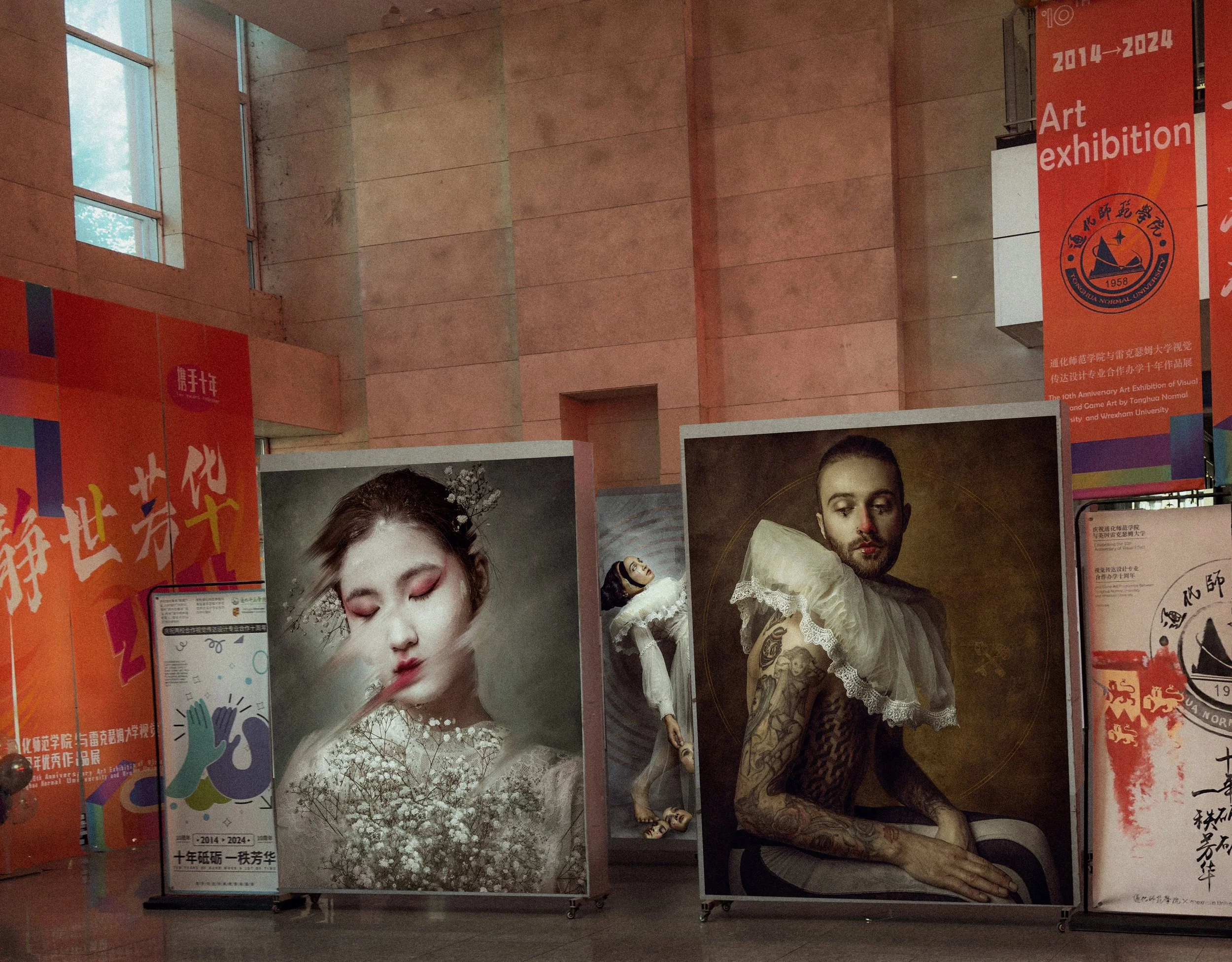 Display of posters and banners for an art exhibition at Tonghua Normal University, featuring portraits of women in traditional and modern styles, with colorful and Chinese text, and a banner indicating a celebration from 2014 to 2024.