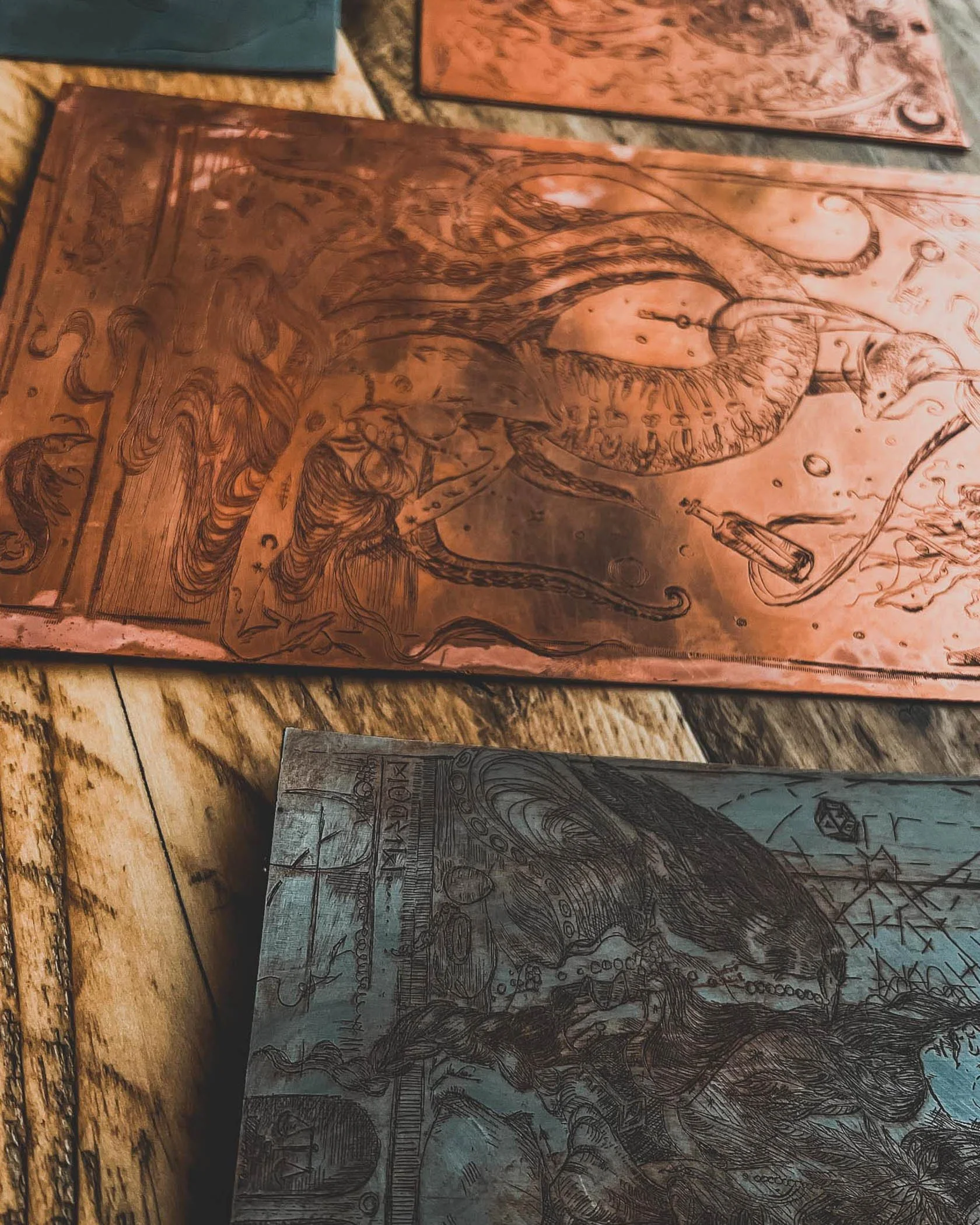 Close-up of engraved artwork on metal plates with intricate designs, depicting a mythical creature or dragon, some recognizable symbols or text, placed on a wooden surface. by Karolina Skorek
